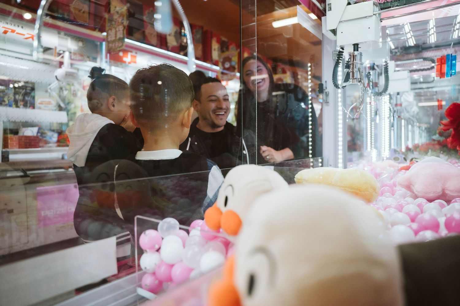 Colorful plush toys and stuffed animals displayed in a claw machine arcade game at an entertainment venue.