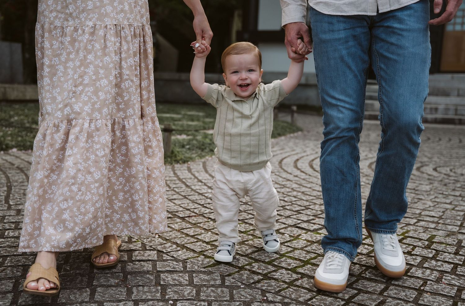 Close-up view of small feet in white shoes walking on cobblestone pavement.