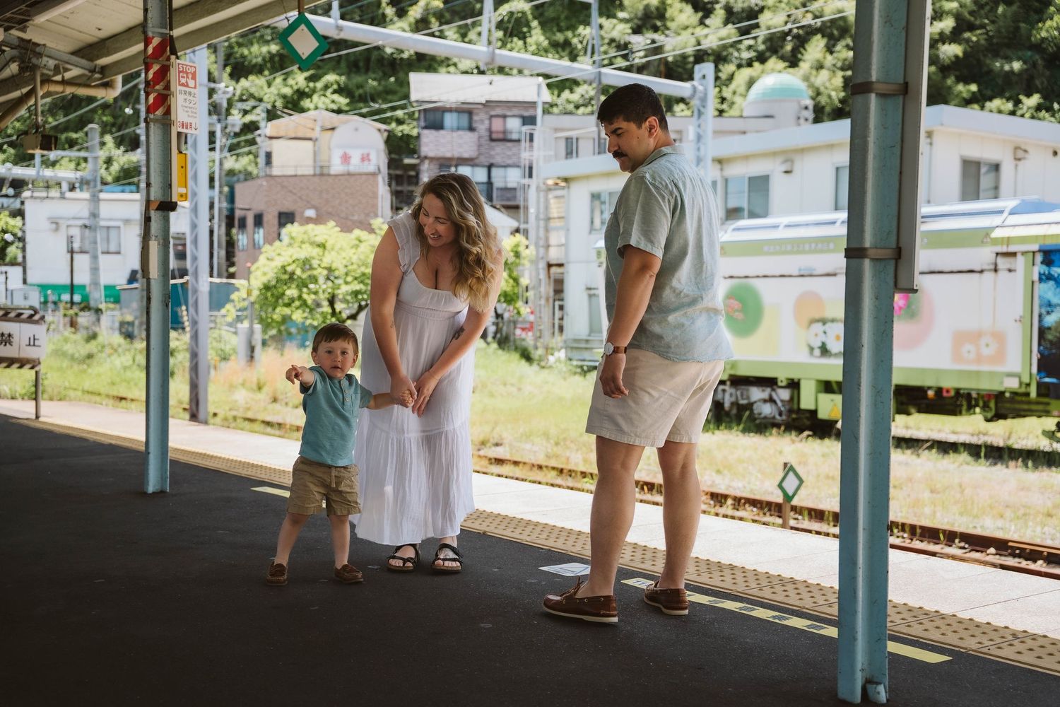 Couple waiting together at a train station platform on a sunny summer day.