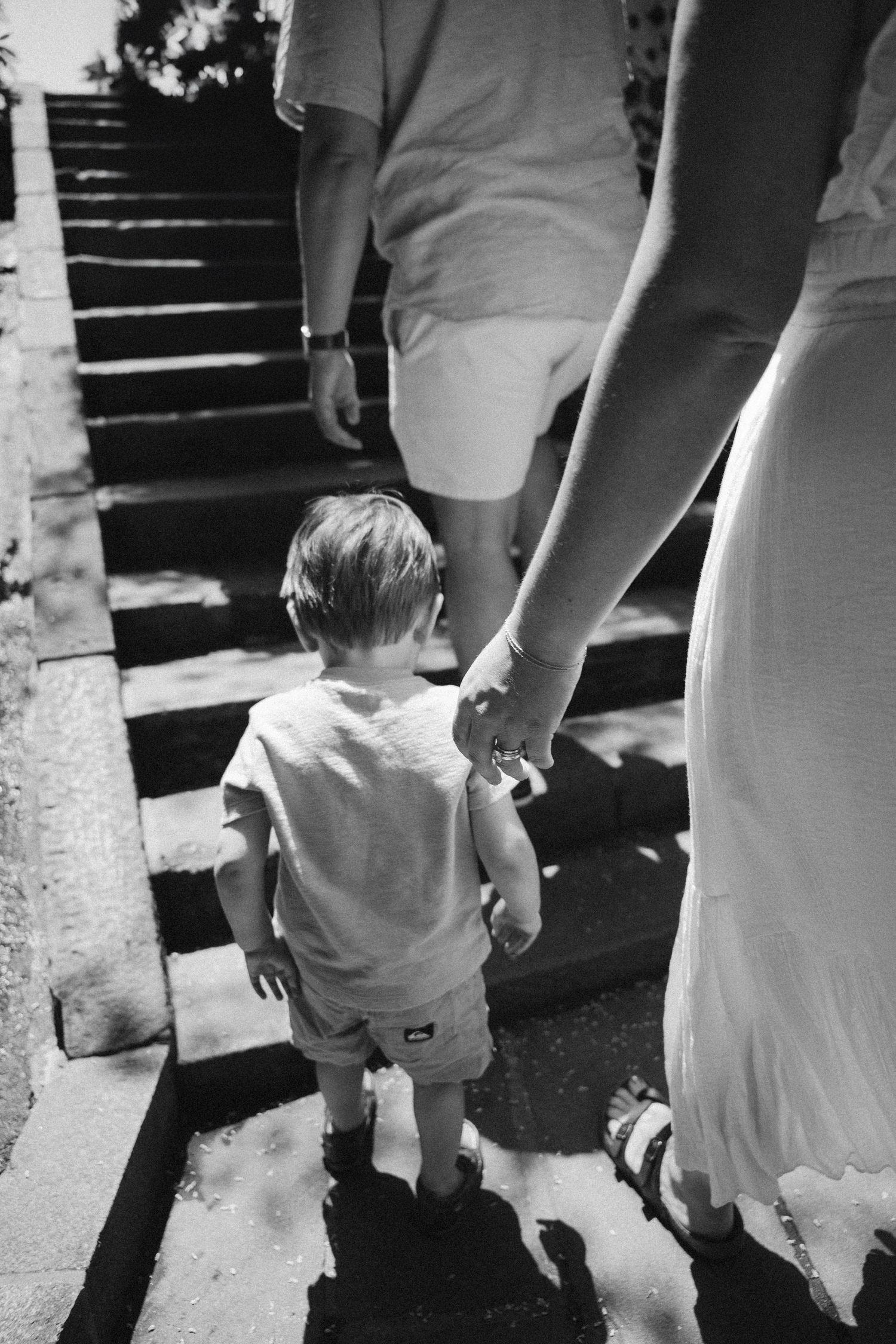 Black and white photo sequence showing a parent and child walking up stairs holding hands.