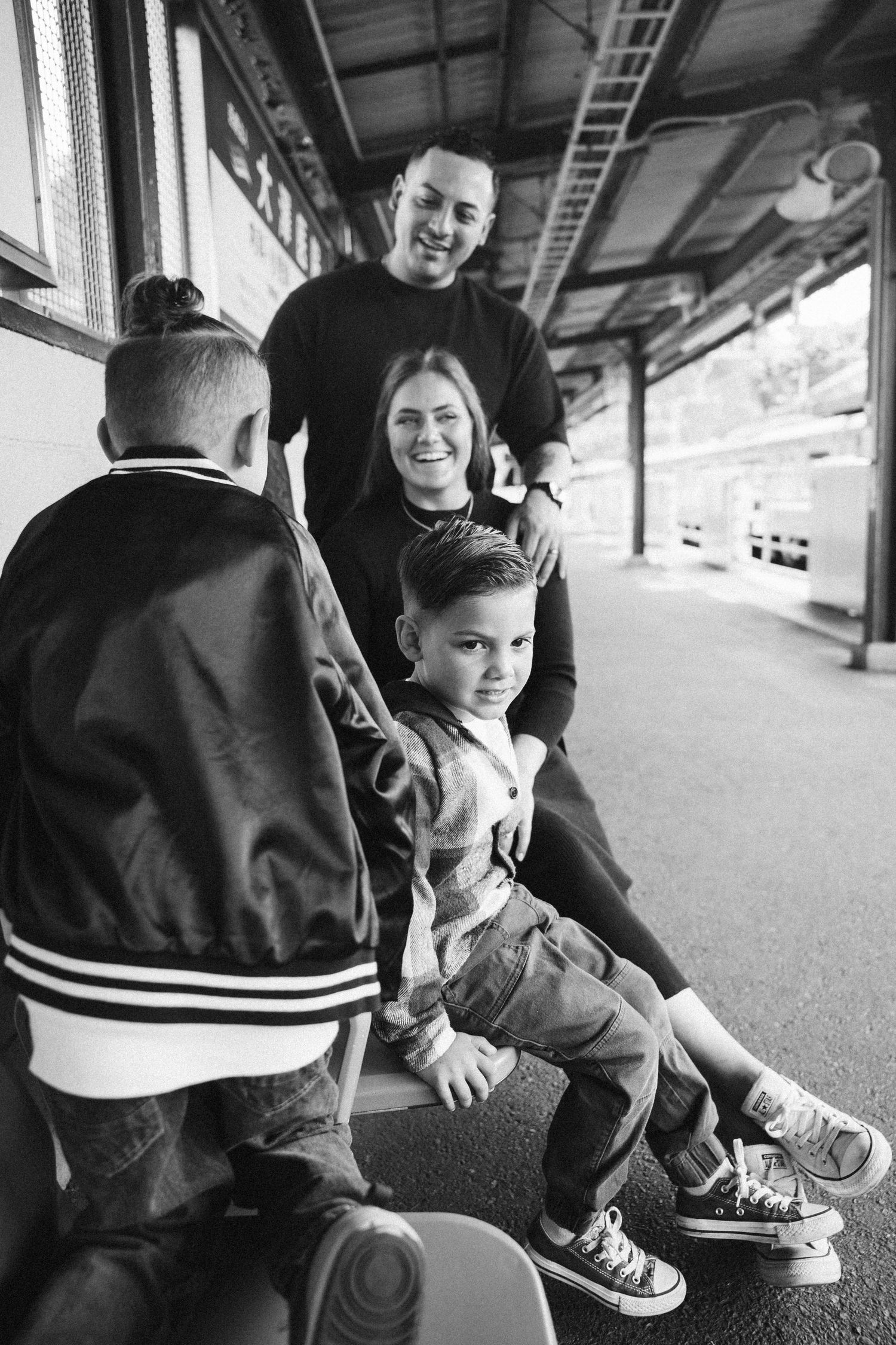 People sitting on a covered platform, focusing on their shoes and feet.