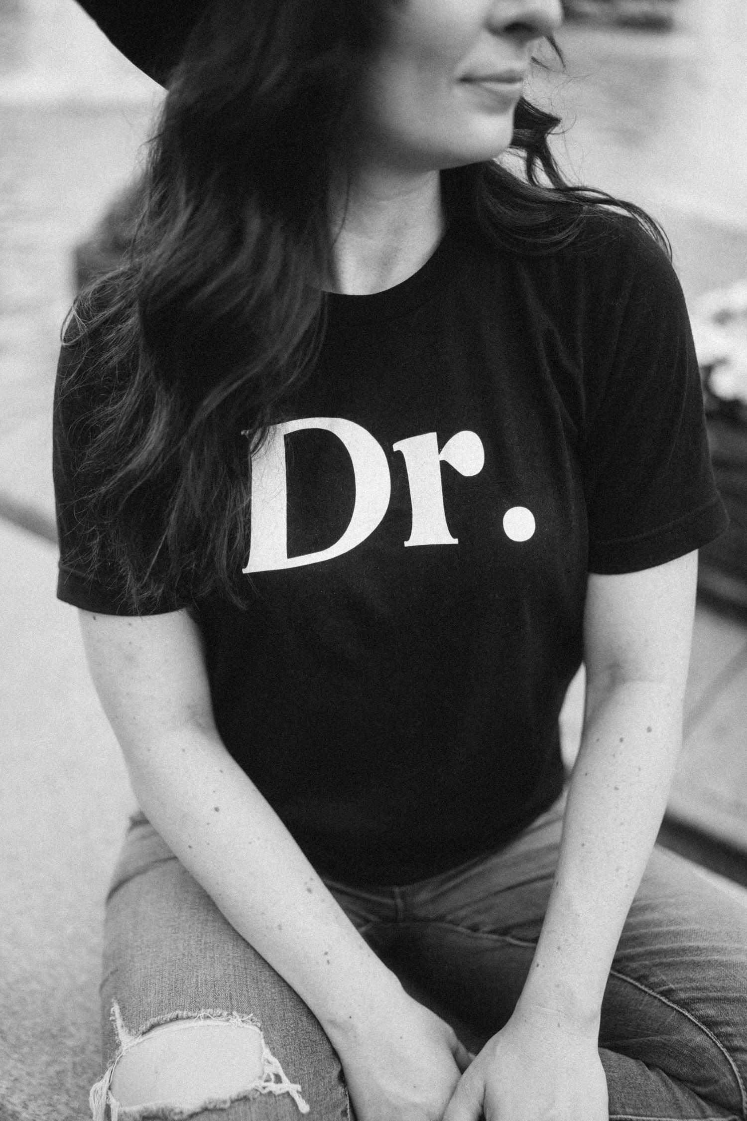 A series of black and white photos showing someone wearing a black t-shirt with text, sitting casually.