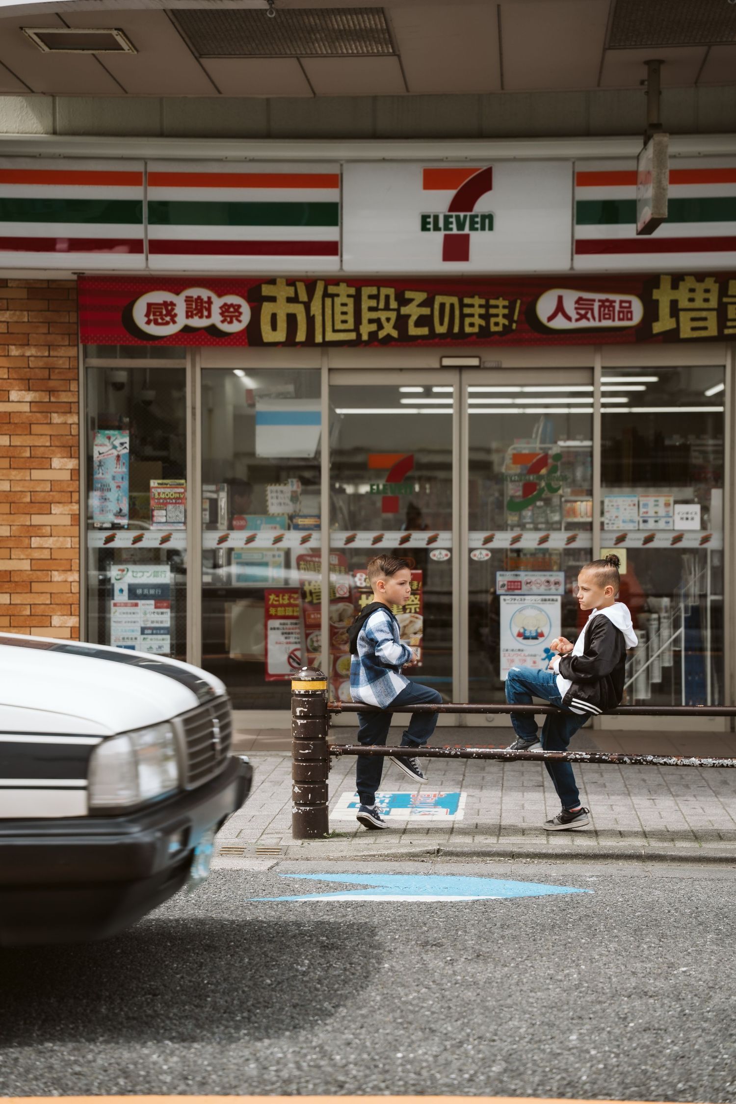 A couple sits outside a 7-Eleven convenience store in Japan, sharing a quiet moment together.