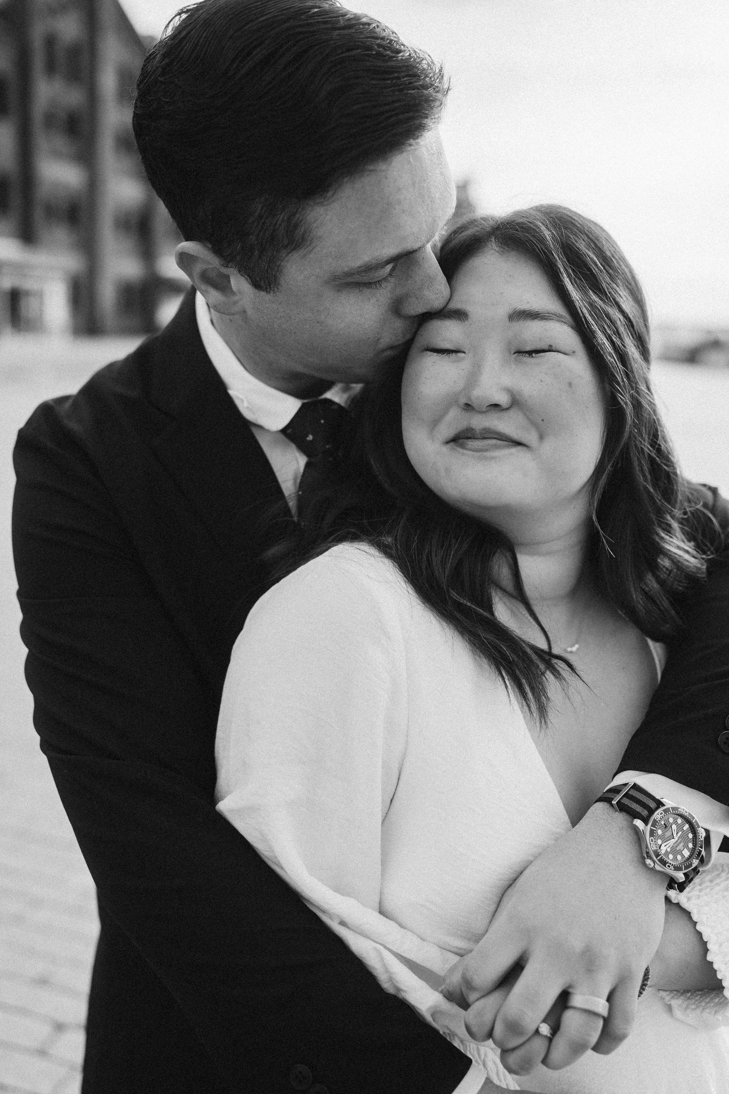 An intimate black and white portrait of a couple sharing a tender moment together outdoors.