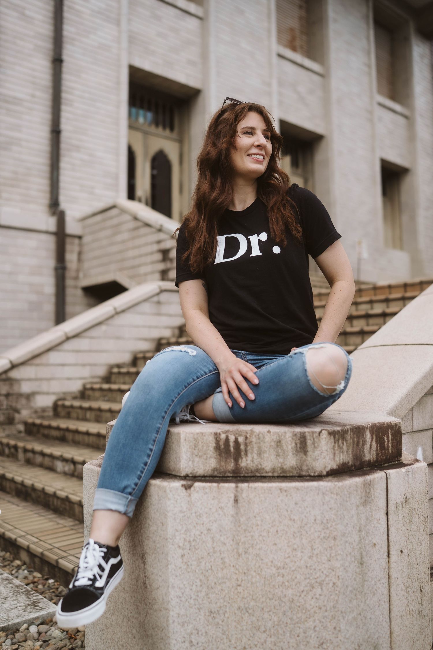 Series of casual poses showing someone in ripped jeans and black shirt sitting on concrete steps of a building.