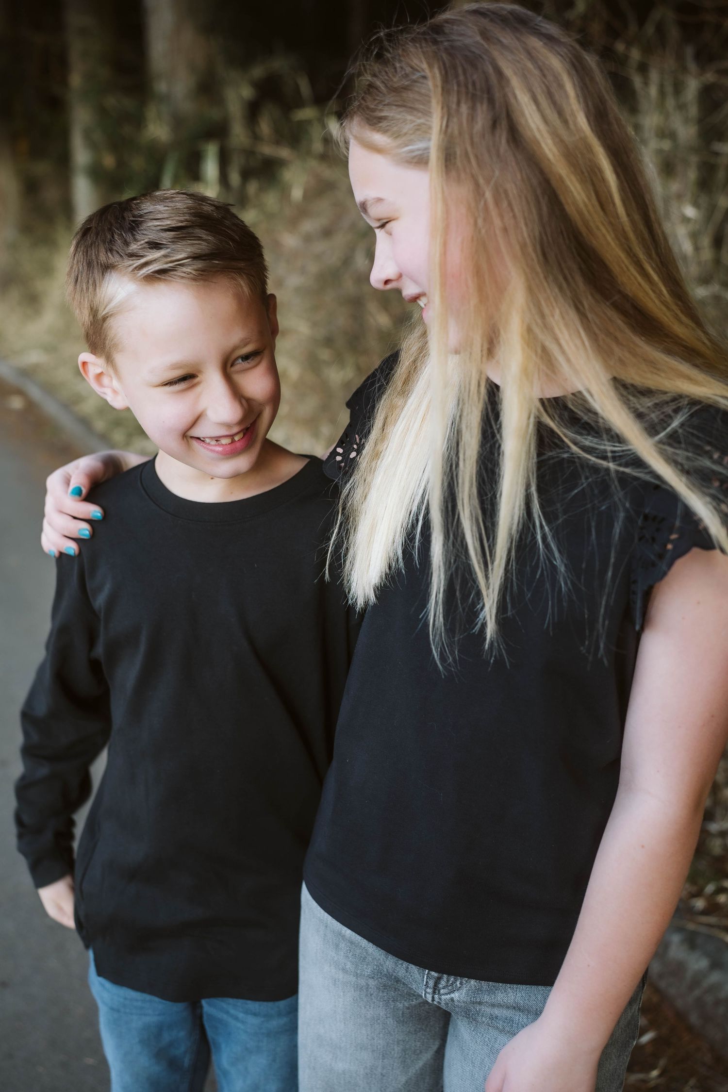 A touching moment showing two people in black tops sharing a laugh and embrace while standing outdoors.