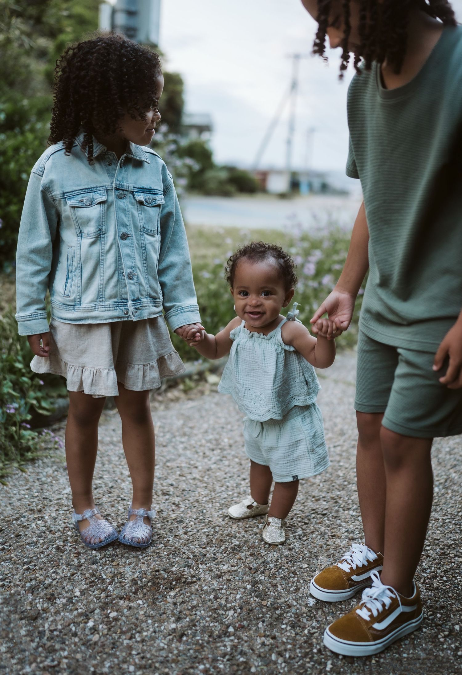 A series of four photos showing small feet wearing sneakers and denim shorts walking on a gravel path.