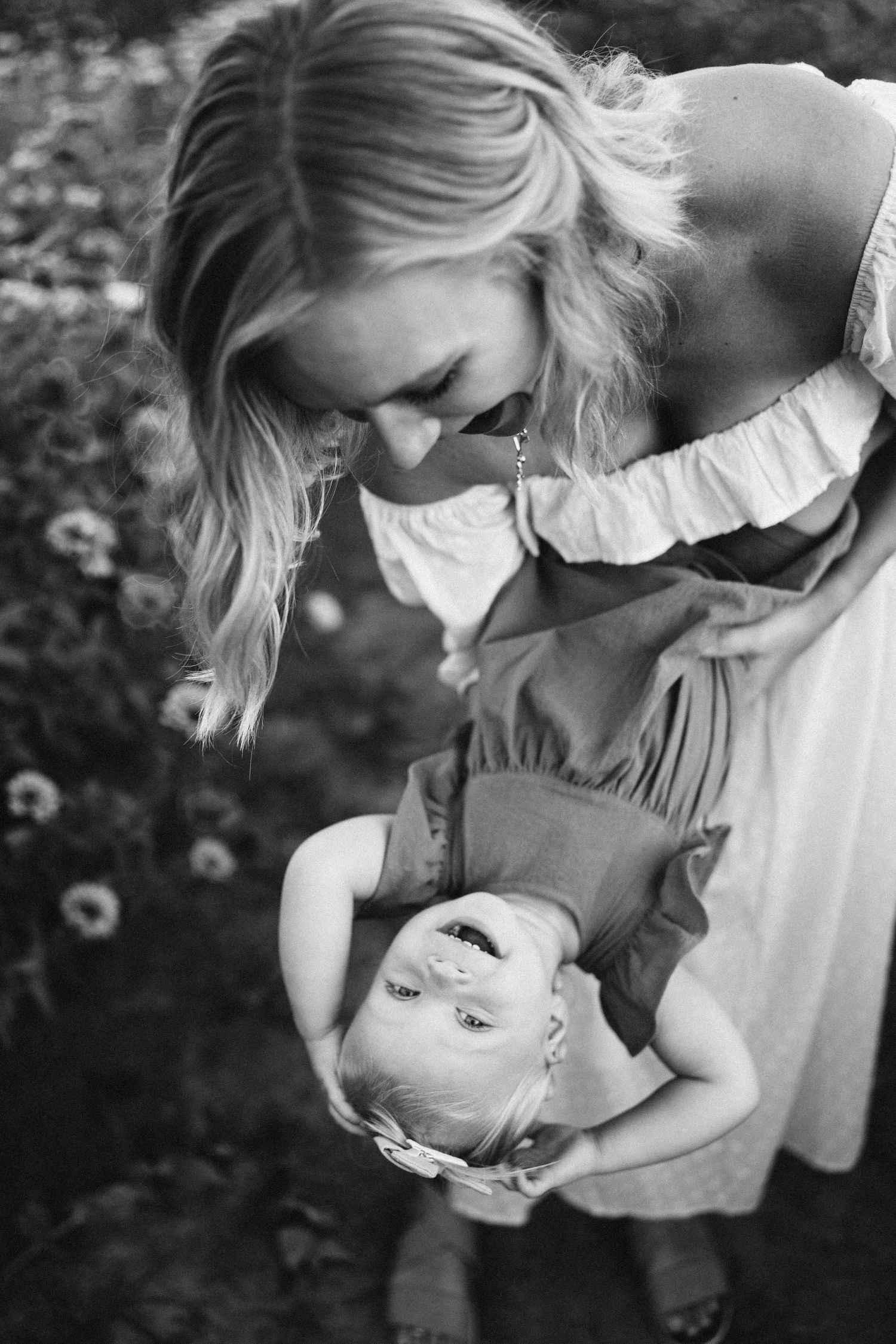 A heartwarming black and white photograph showing a tender moment between a parent and child in a garden setting.