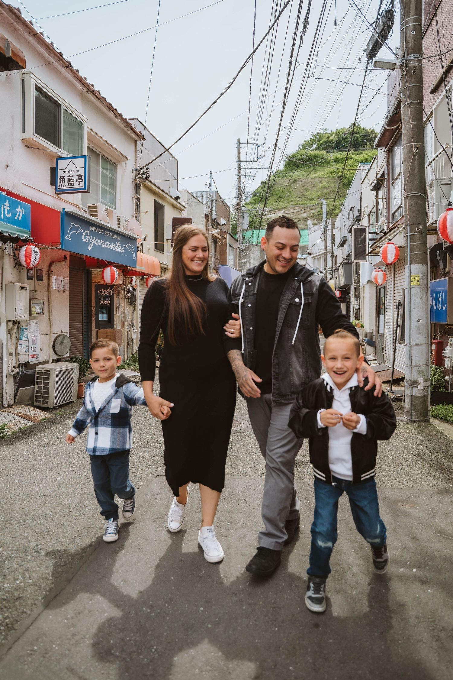Family walking together down a quaint Japanese street lined with traditional buildings and lanterns.