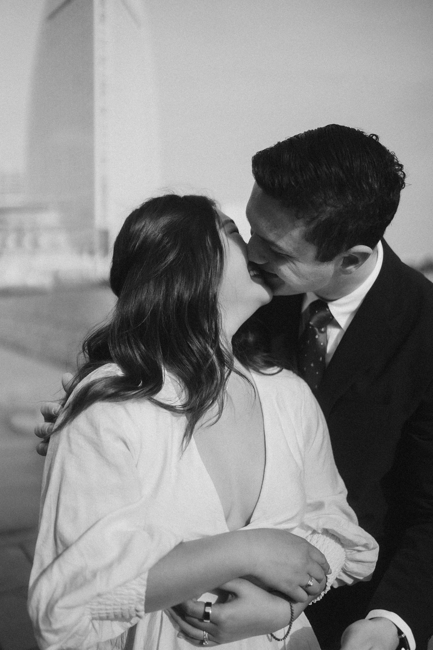 A romantic black and white portrait of a couple sharing an intimate moment in formal attire.