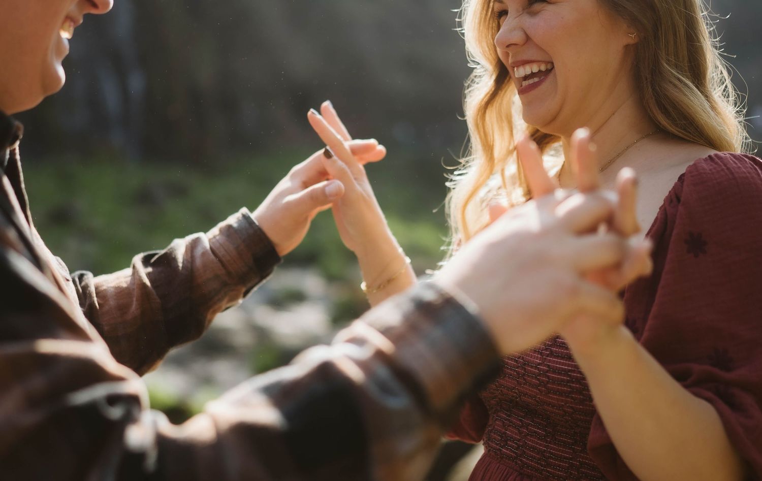 A couple shares a playful and joyful moment together outdoors in warm sunlight.
