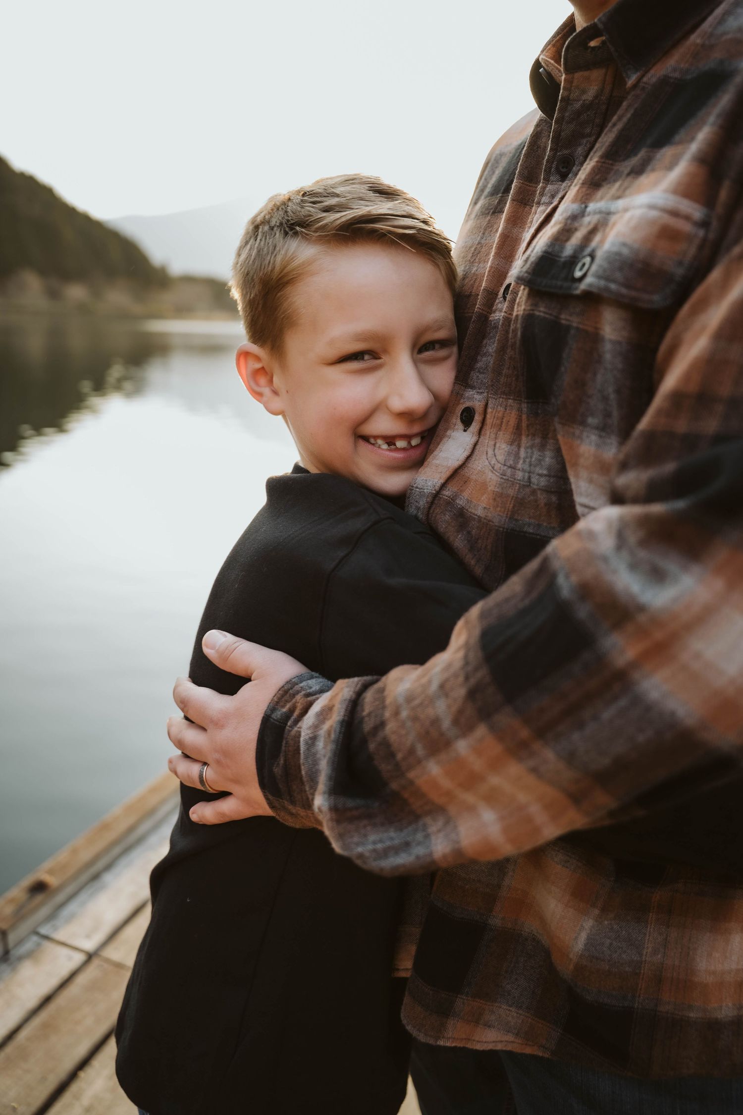 A tender family moment shared between parent and child on a wooden dock by a serene lake.