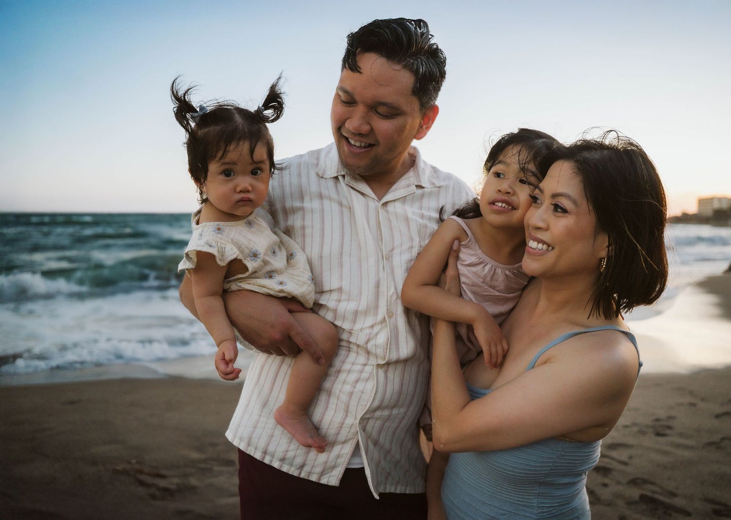 A loving family shares joyful moments together during a sunset photoshoot at the beach.