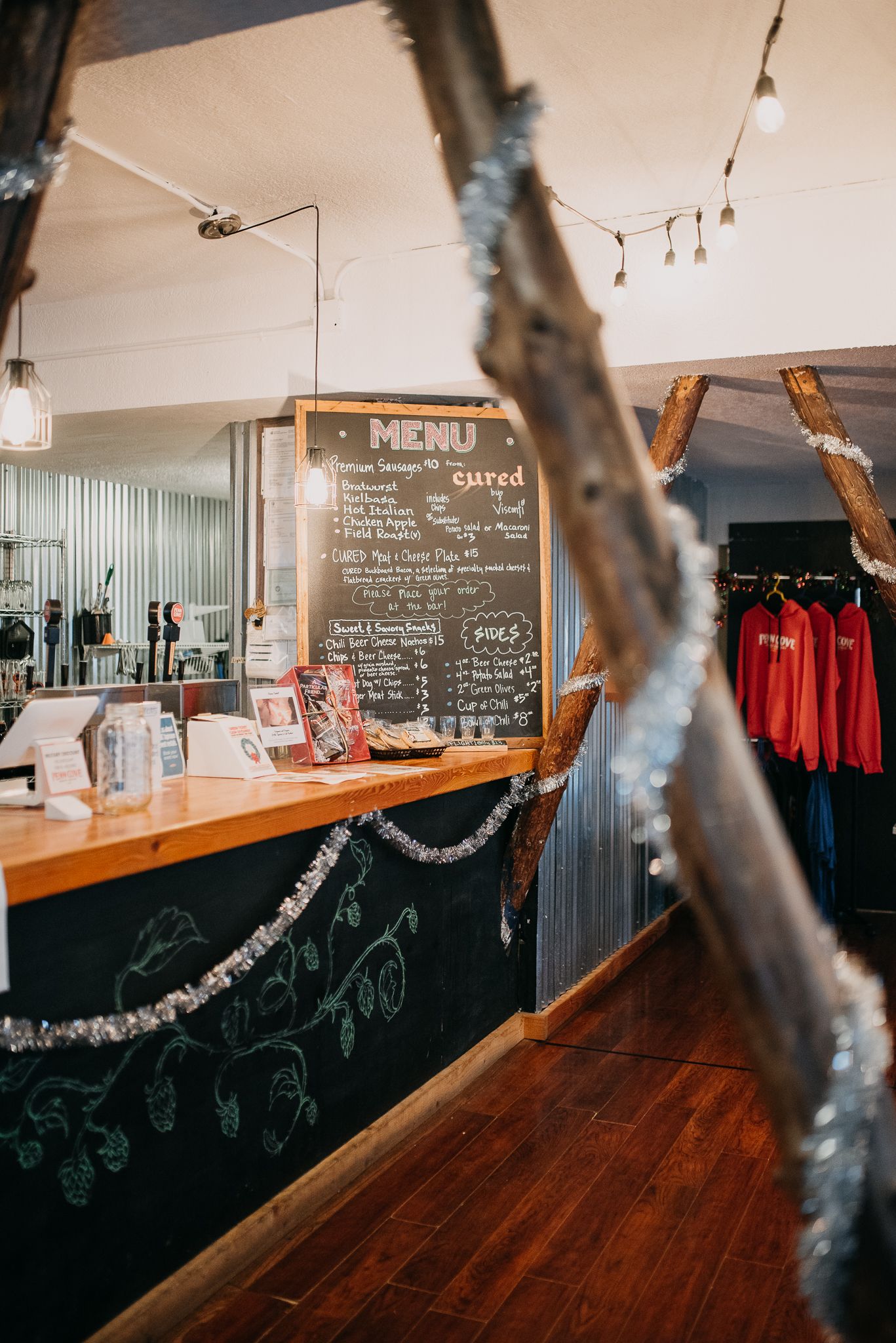 Rustic brewery interior with chalkboard menu and merchandise display at the counter.