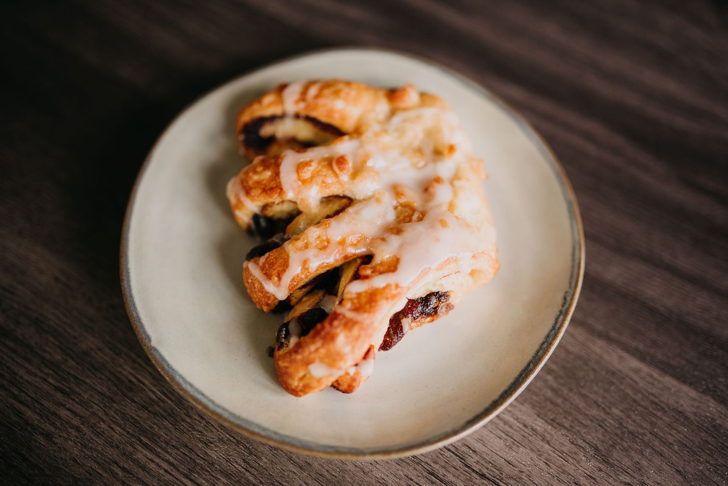 Glazed pastry turnovers with icing drizzle served on a ceramic plate.