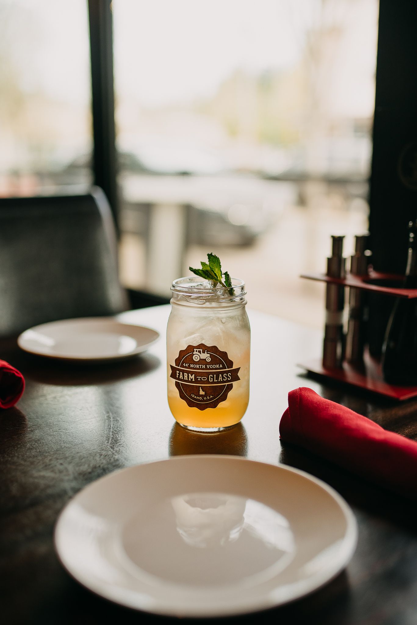 Farm to Glass branded mason jar cocktail with mint garnish on restaurant table.