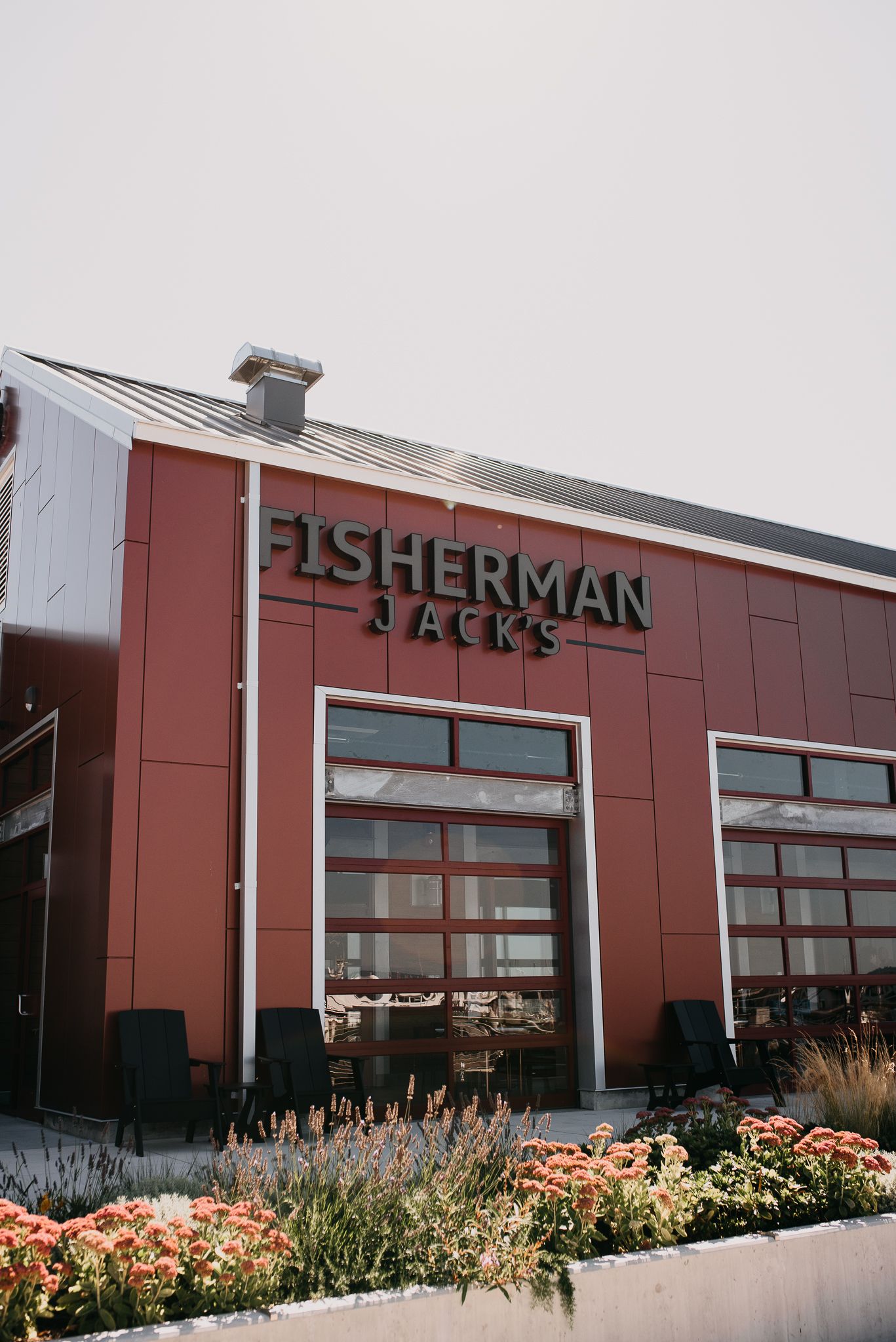Exterior of Fisherman Jacks red barn-style restaurant with flower garden.
