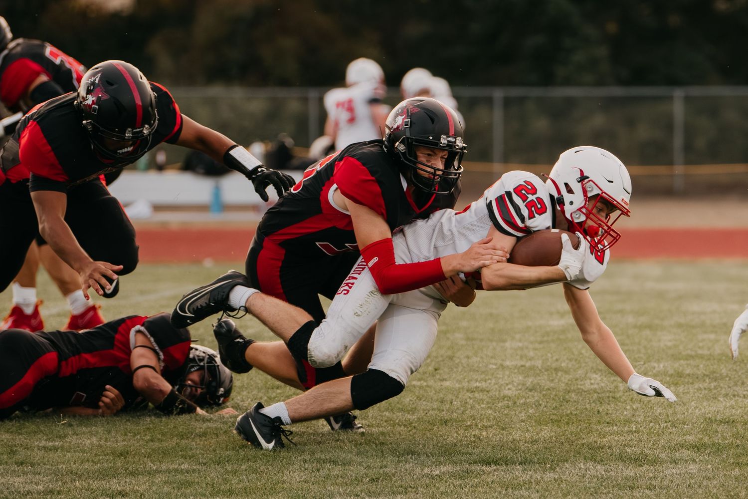 Football player being tackled during competitive youth game on outdoor field.