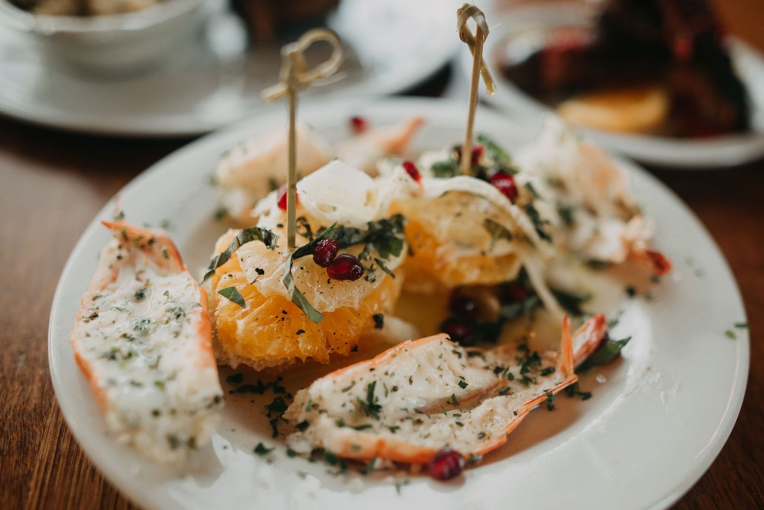 Elegant seafood dish with lobster and herbs served on a white plate at a restaurant.