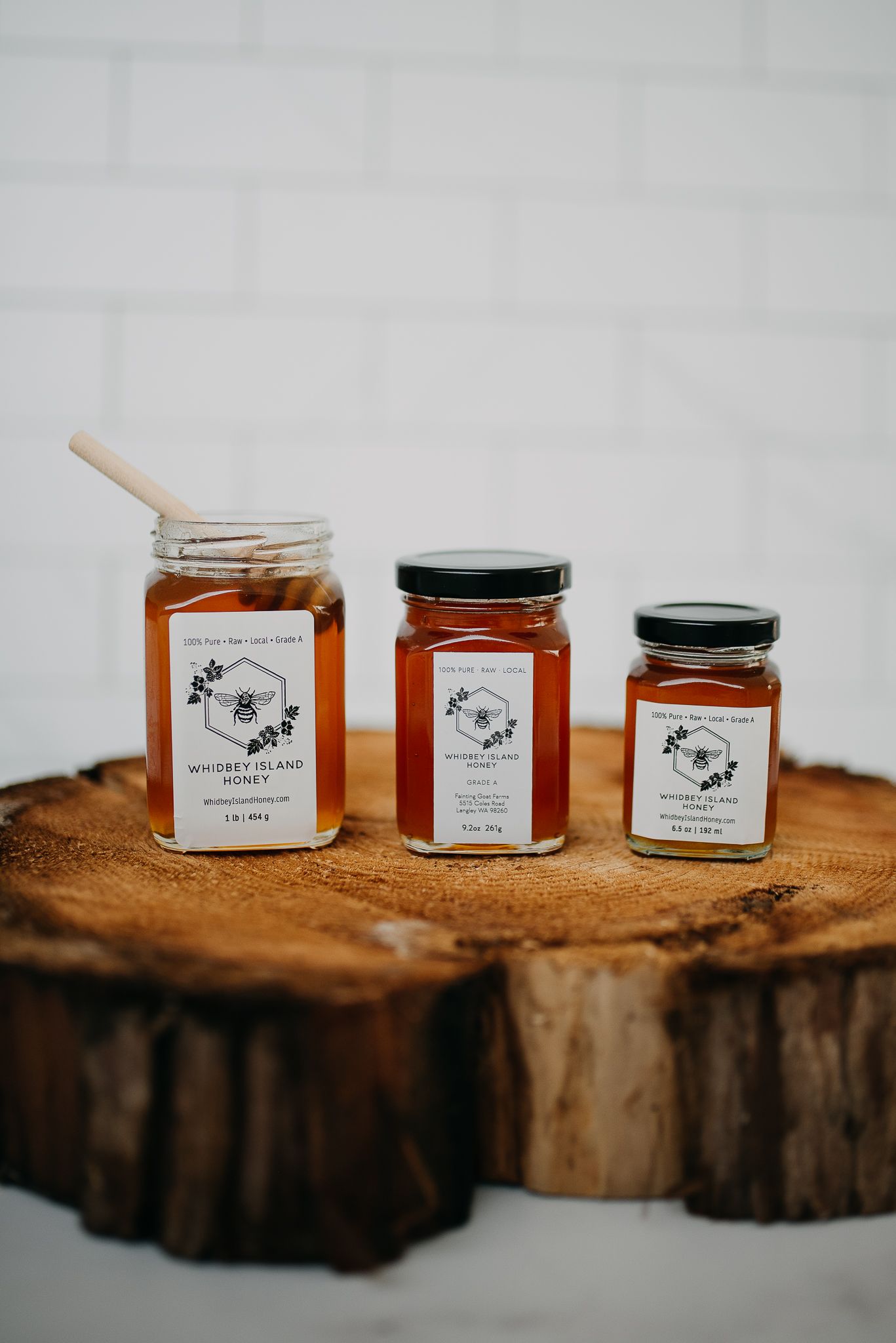 Three jars of Whidbey Island Honey displayed on a rustic wood slice cutting board.