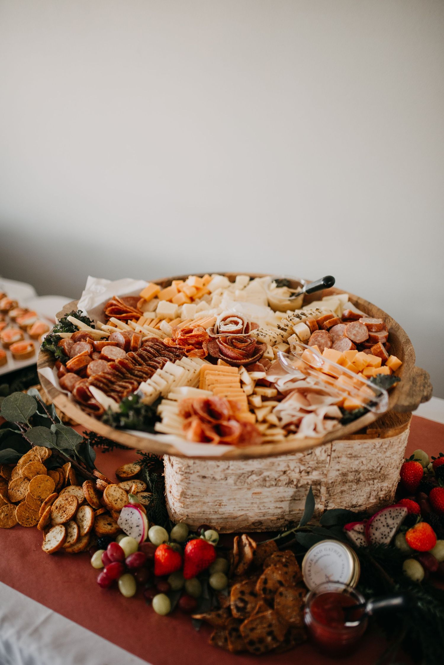 Elegant charcuterie board with meats, cheeses, nuts, and fruits on a rustic wooden display at a wedding reception.