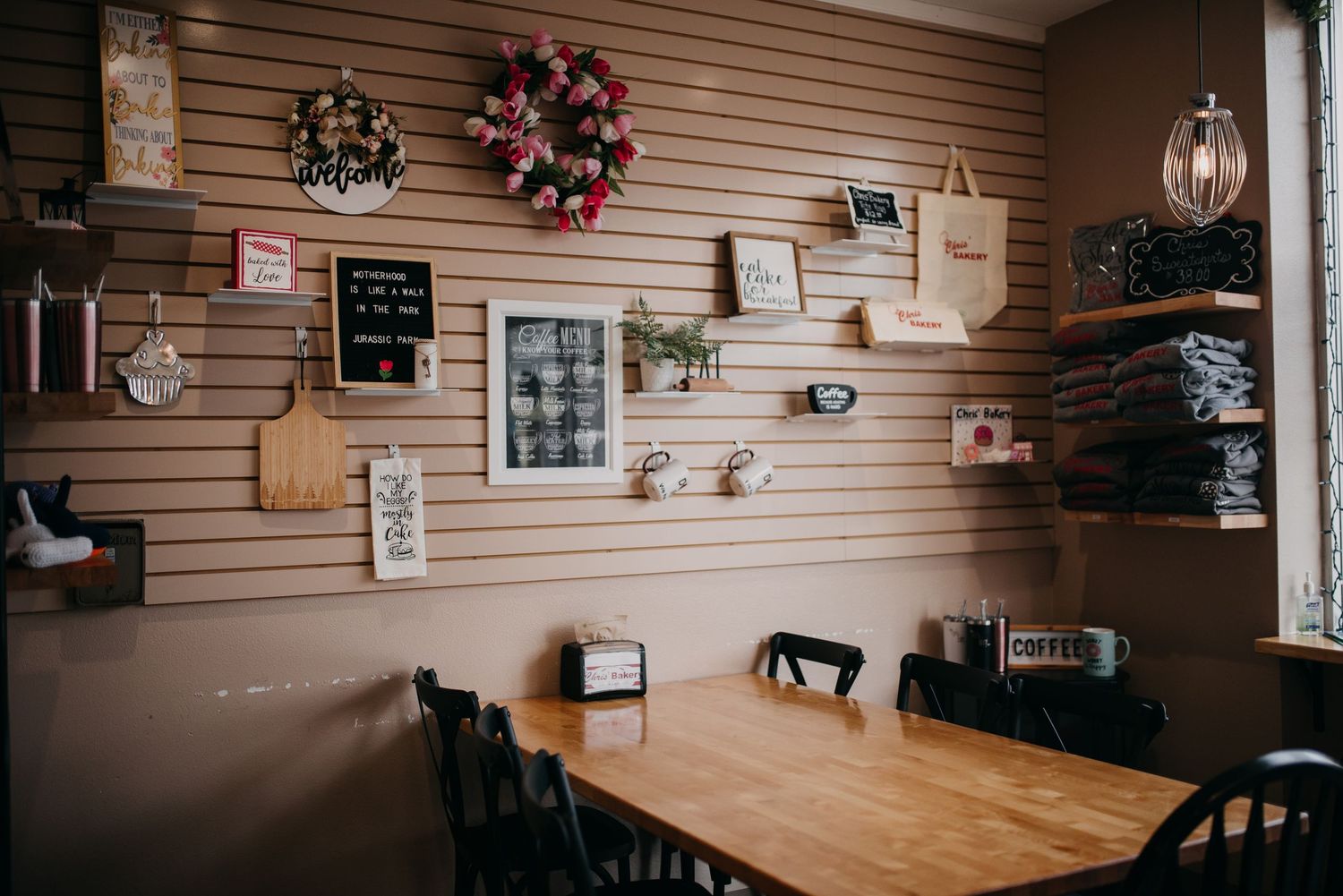 Cozy cafe interior with decorative wall display, wooden table, and black chairs.
