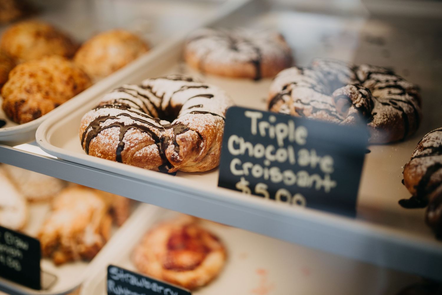 Triple chocolate croissant and assorted pastries displayed in a bakery glass case.