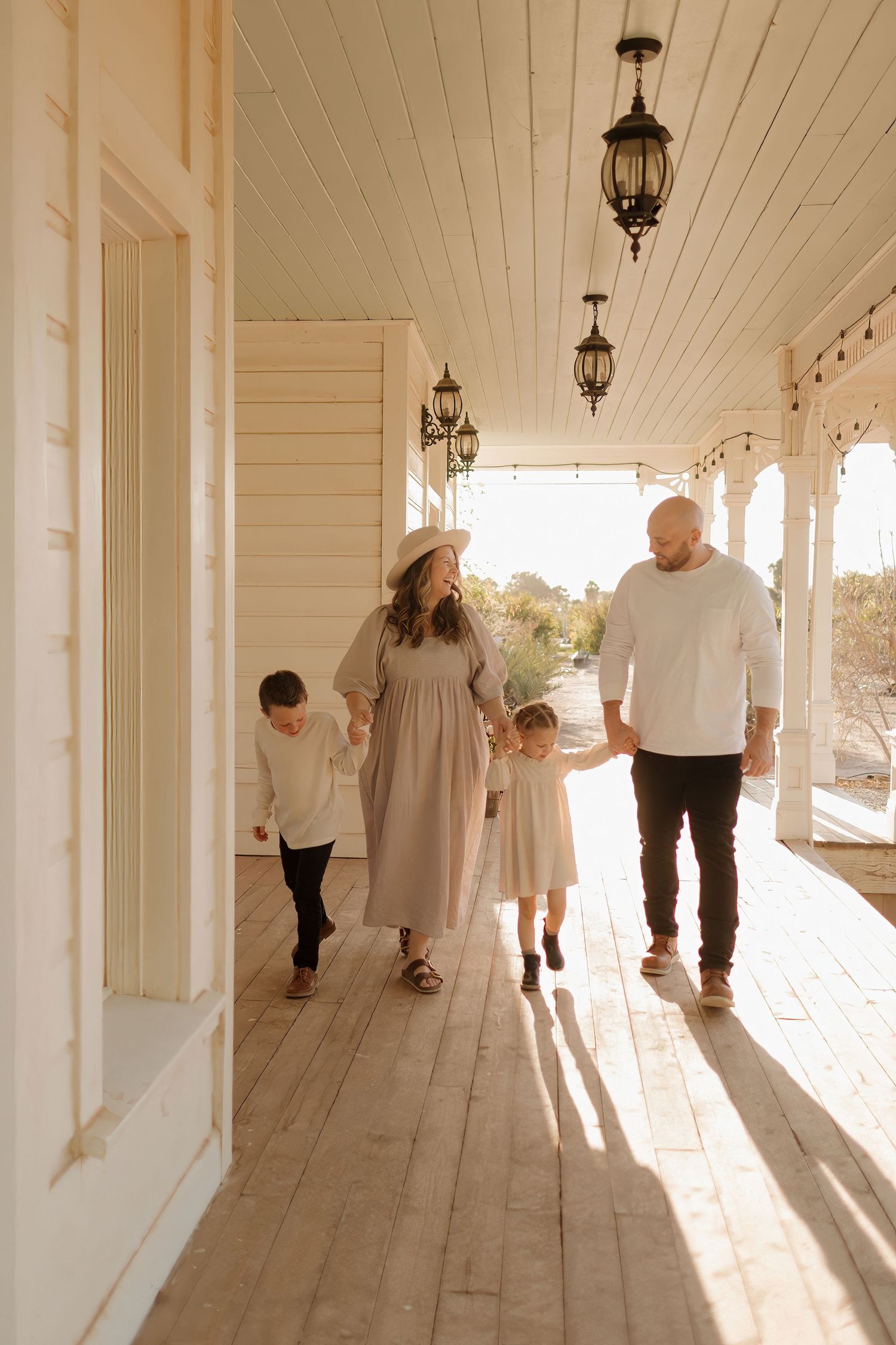 Family walking together on sunlit farmhouse porch with vintage lanterns.