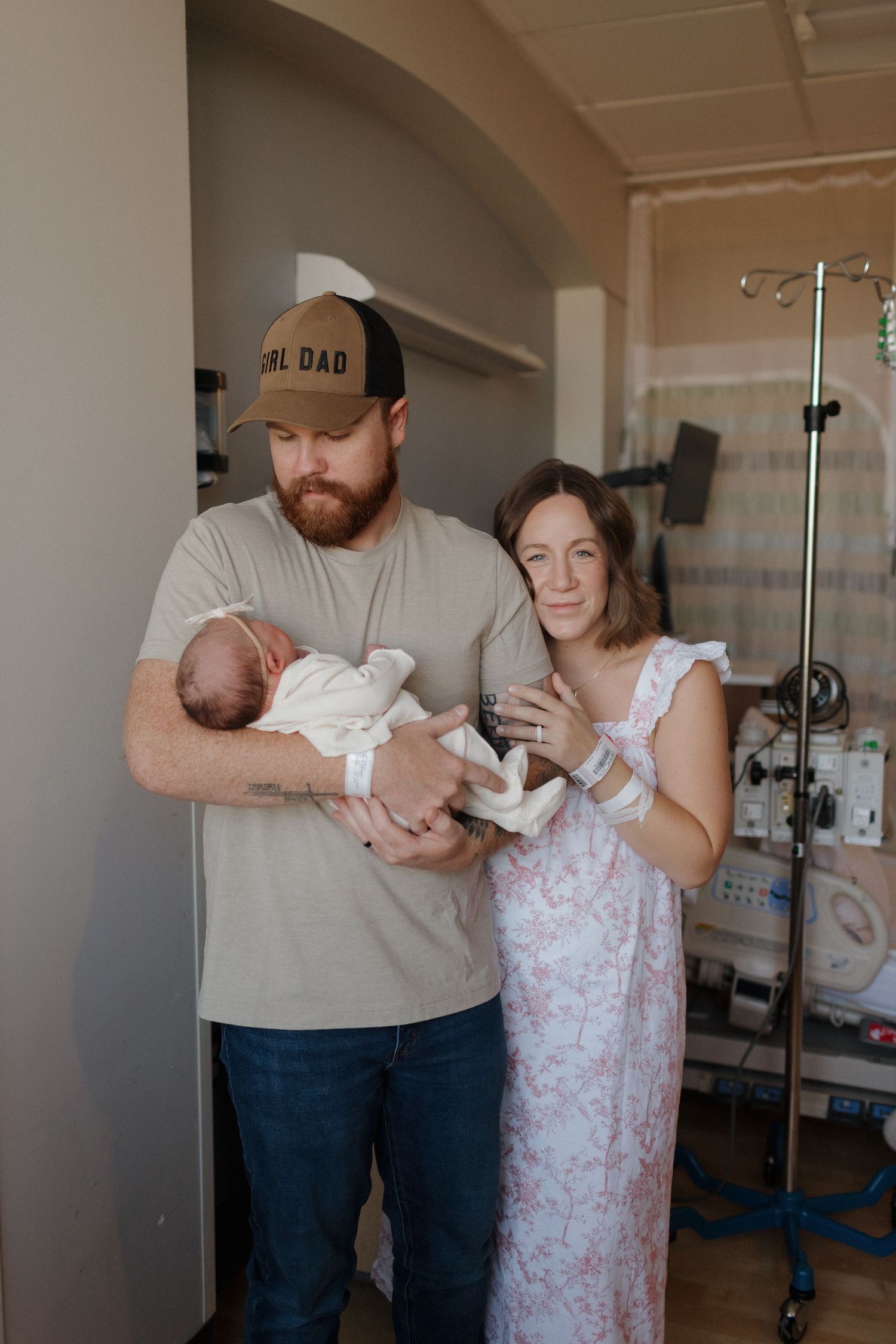 Parents stand together in a hospital room holding their newborn baby in a tender moment after birth.