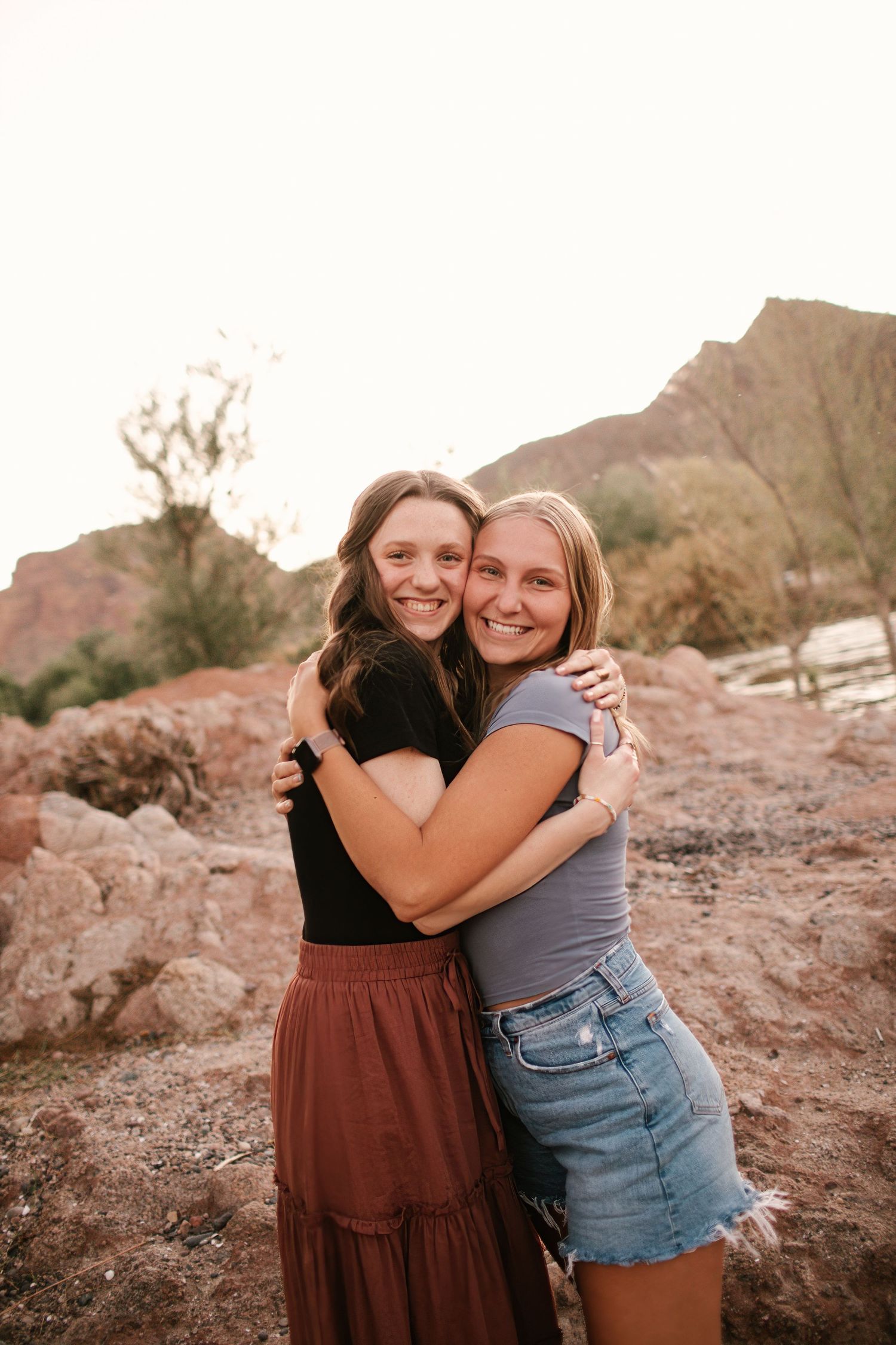 Graduating seniors embracing outdoors during golden hour in desert mountain setting.