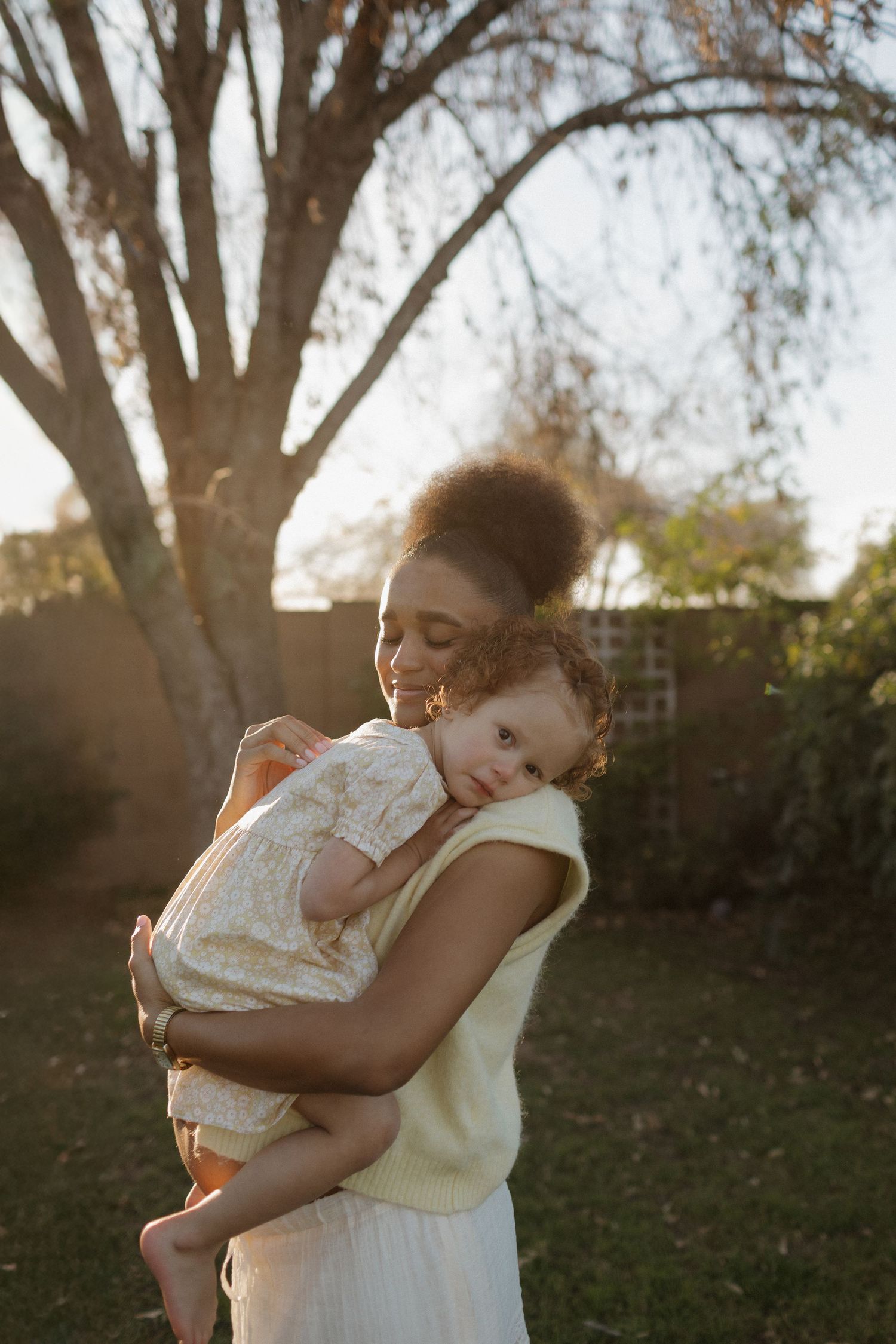 A tender moment between parent and child embracing in warm golden sunlight under autumn trees.