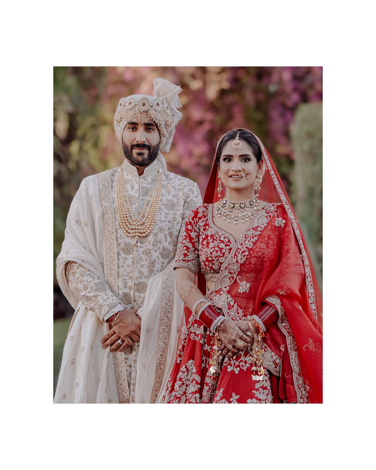 Traditional Indian wedding couple in elegant white sherwani and red bridal lehenga.