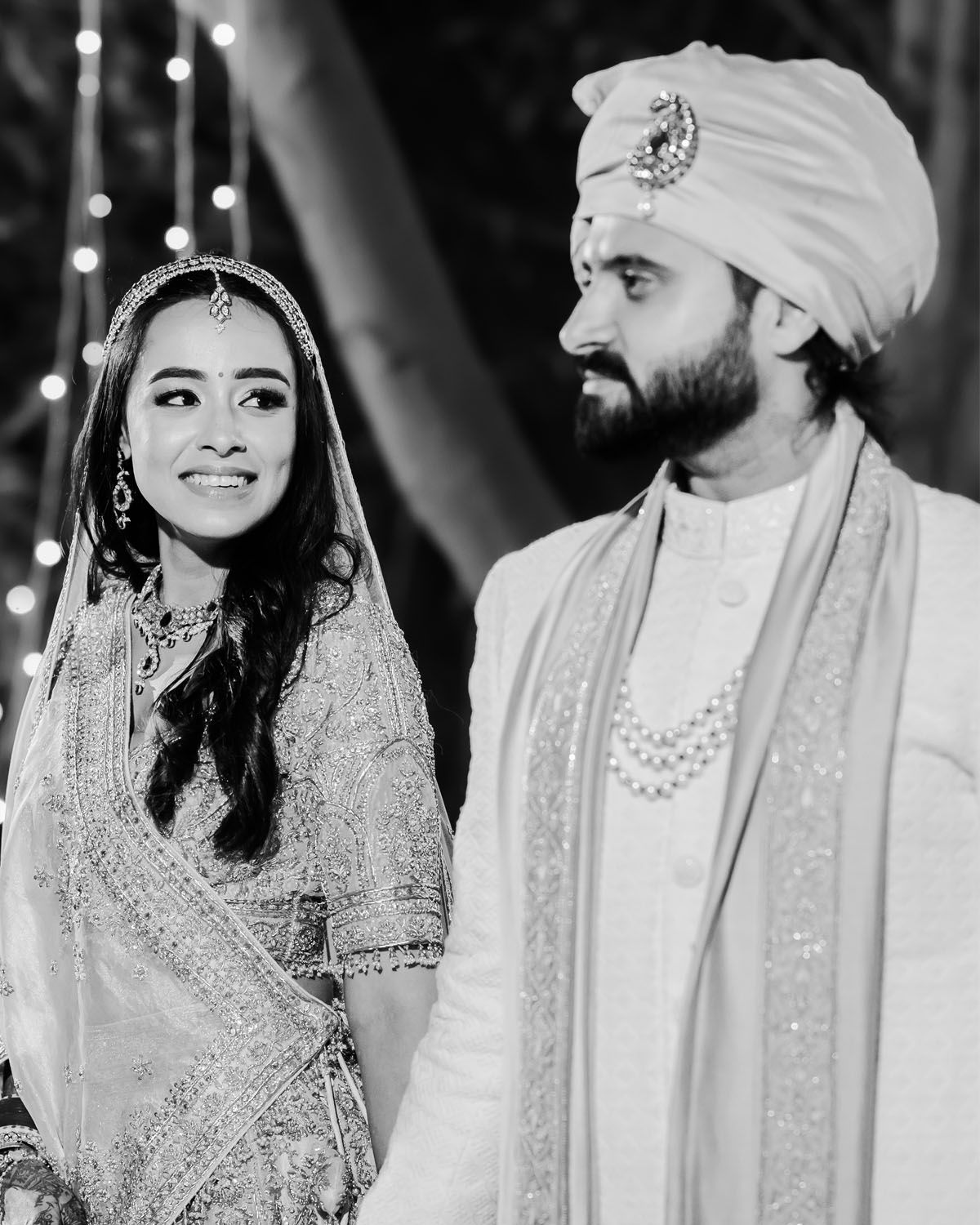 Black and white candid wedding photo showing traditional Indian ceremony attire.