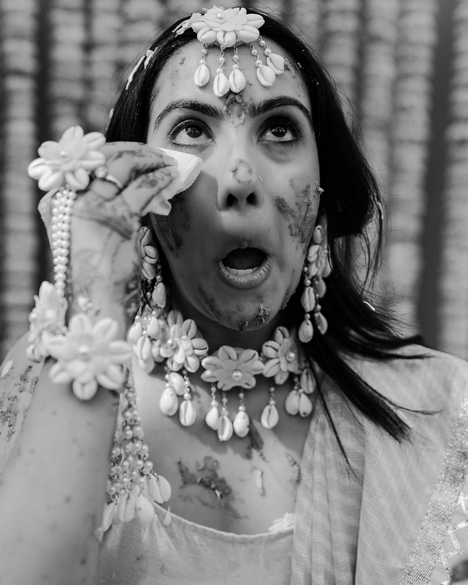 Black and white photo of a woman in floral jewelry and headpiece with an expressive open-mouth pose.
