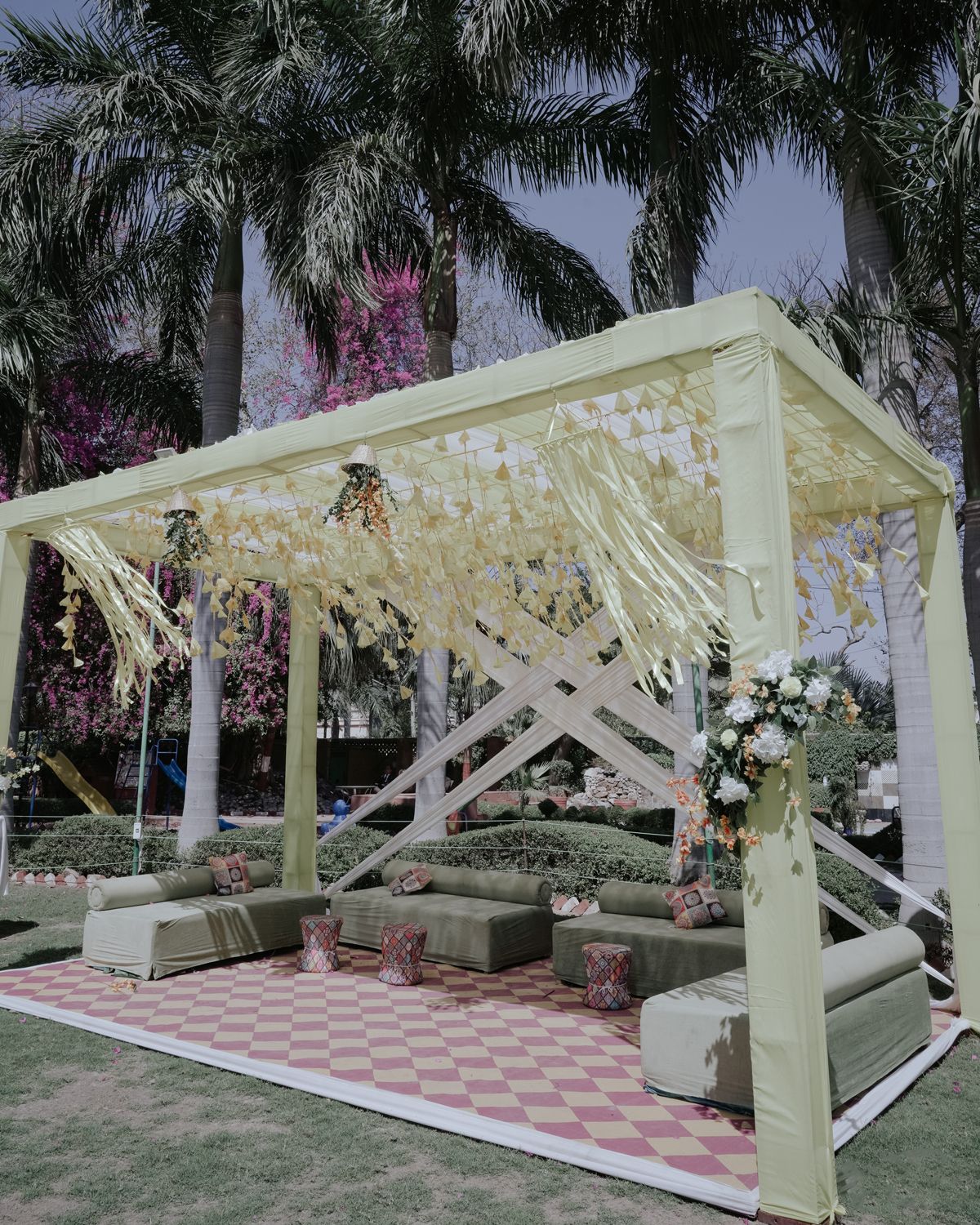 Outdoor wedding seating area with white canopy and palm trees.