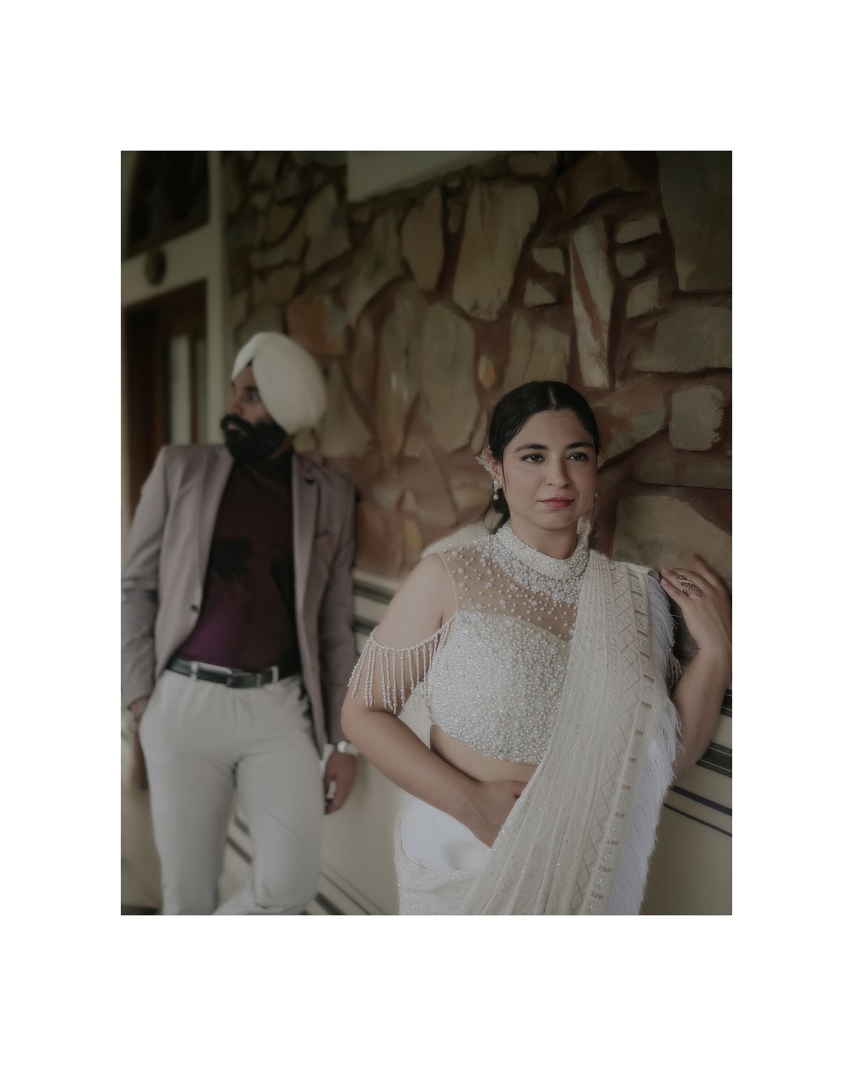 Stylish fashion portrait featuring traditional Indian attire against a stone wall backdrop.