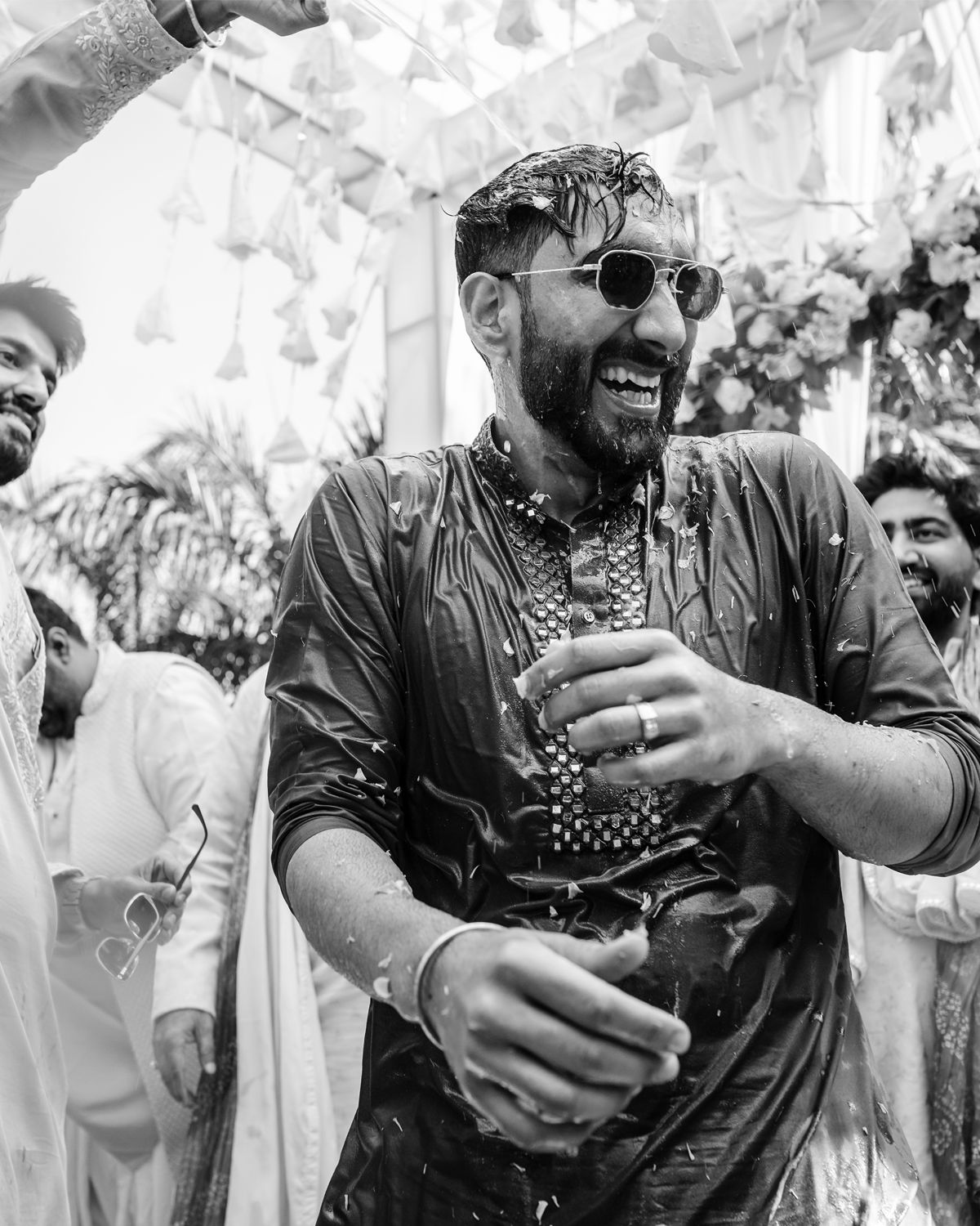 Black and white photo captures celebratory moment with confetti at an Indian wedding ceremony.