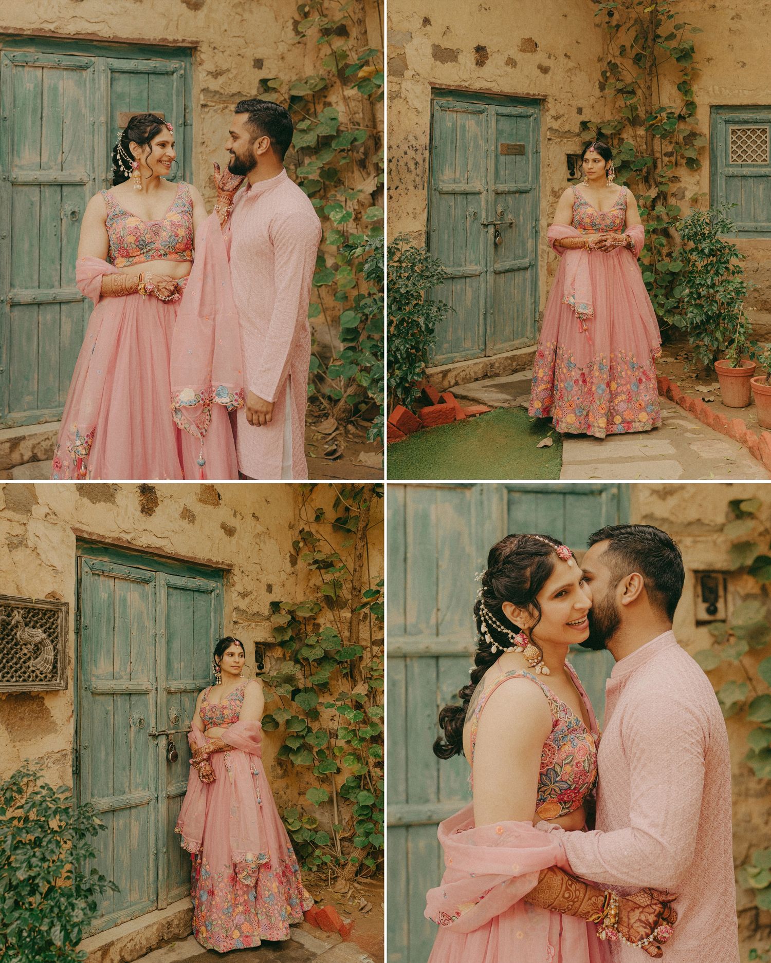 Couple in matching pink Indian outfits posing together near a rustic teal door surrounded by greenery.