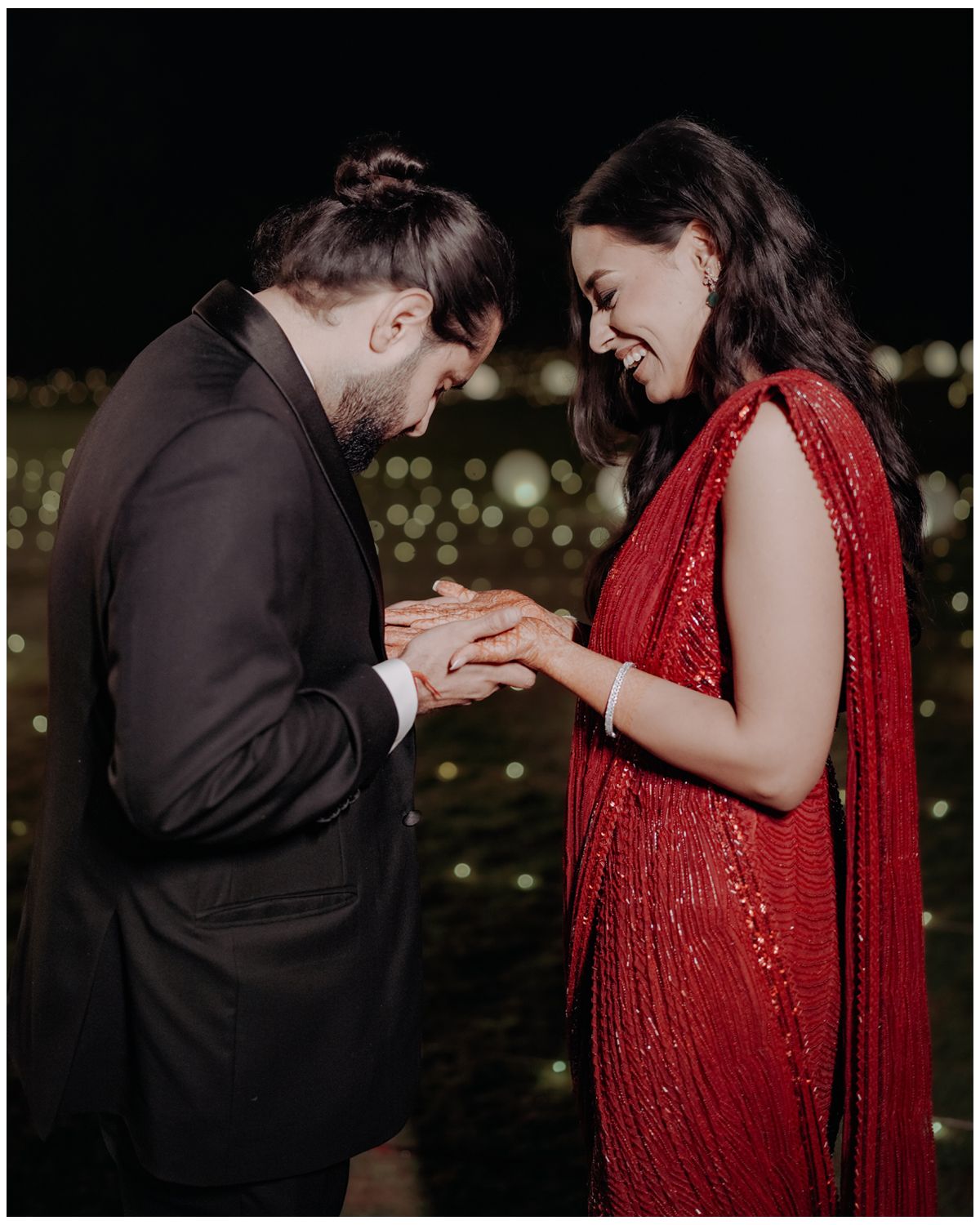A romantic proposal moment captured at night with twinkling lights in the background, featuring elegant formal attire.