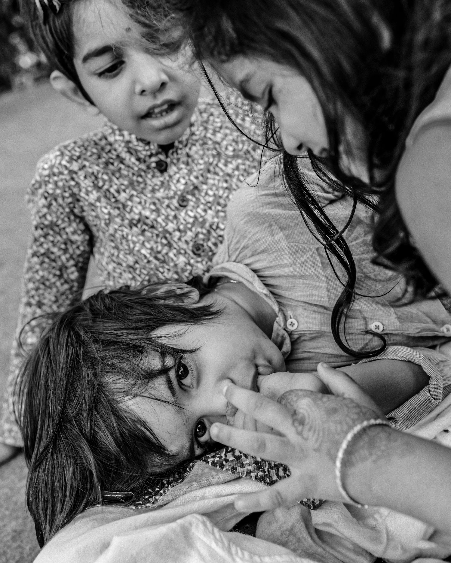 Black and white photo of a mother breastfeeding a toddler while an older child looks on tenderly.
