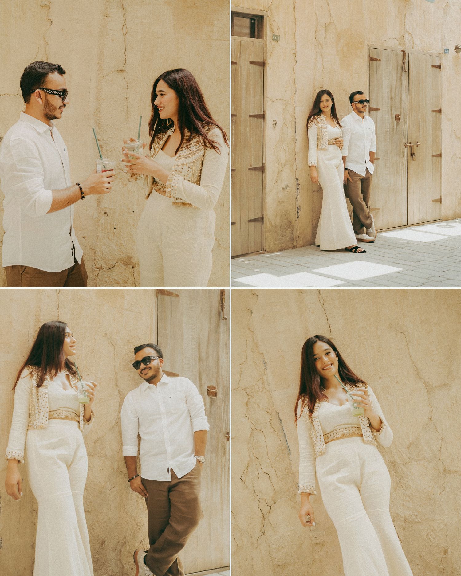 Couple in white outfits posing against beige stone walls in a romantic outdoor photoshoot session.