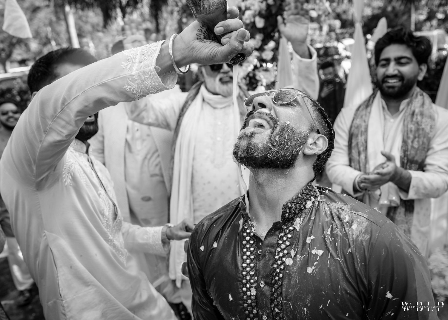 Black and white photograph of celebratory water splashing during wedding festivities.