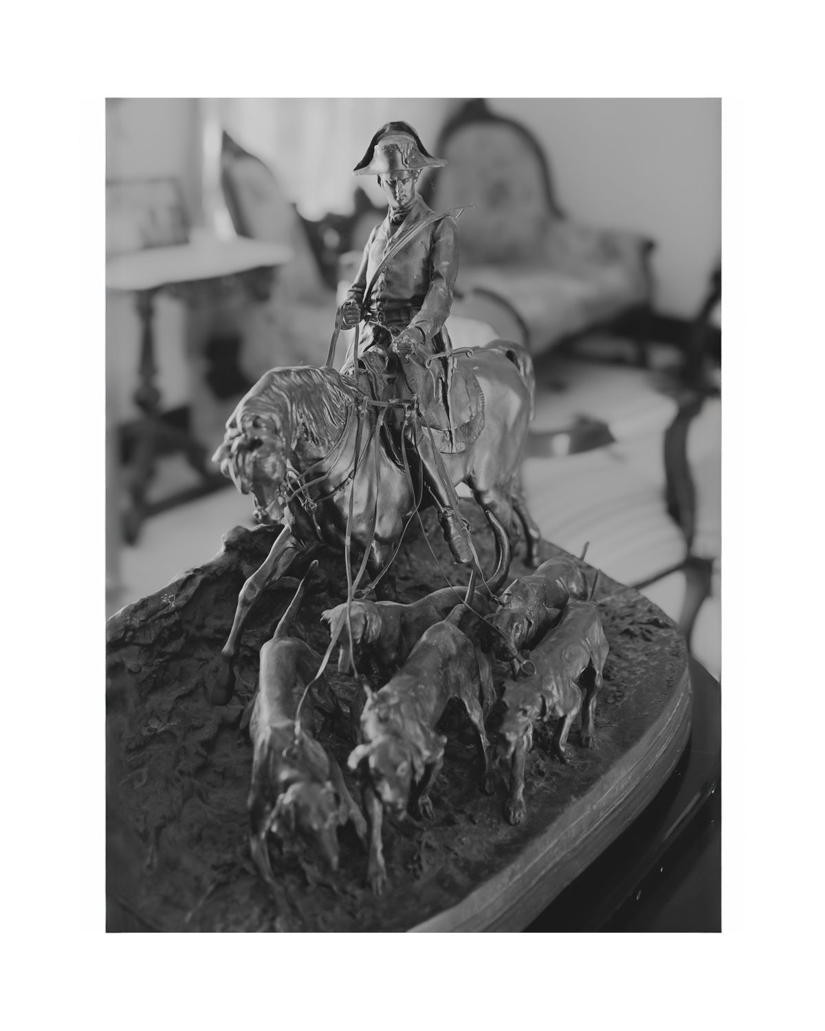 Vintage sculpture depicting cowboy on horseback herding cattle.