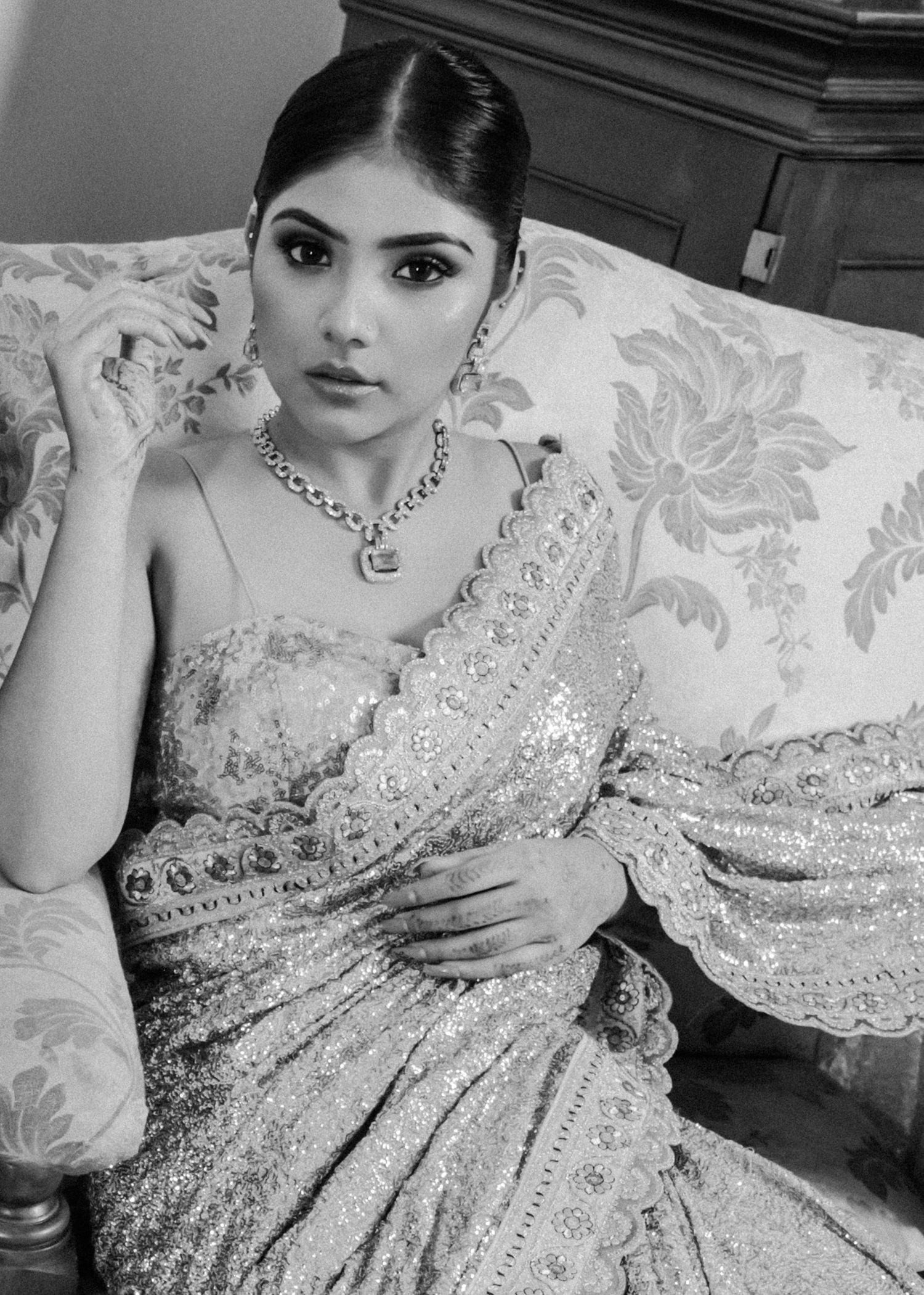 Elegant black and white portrait of someone in an ornate saree with delicate embroidery and statement necklace.