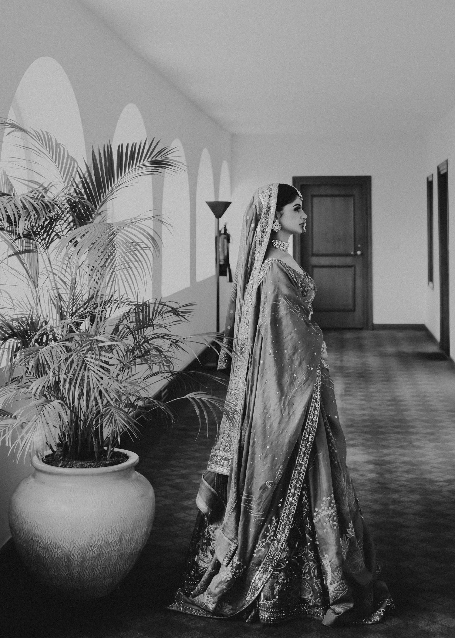 A series of vintage black and white photographs showing potted palm plants and draped fabric in a long corridor.