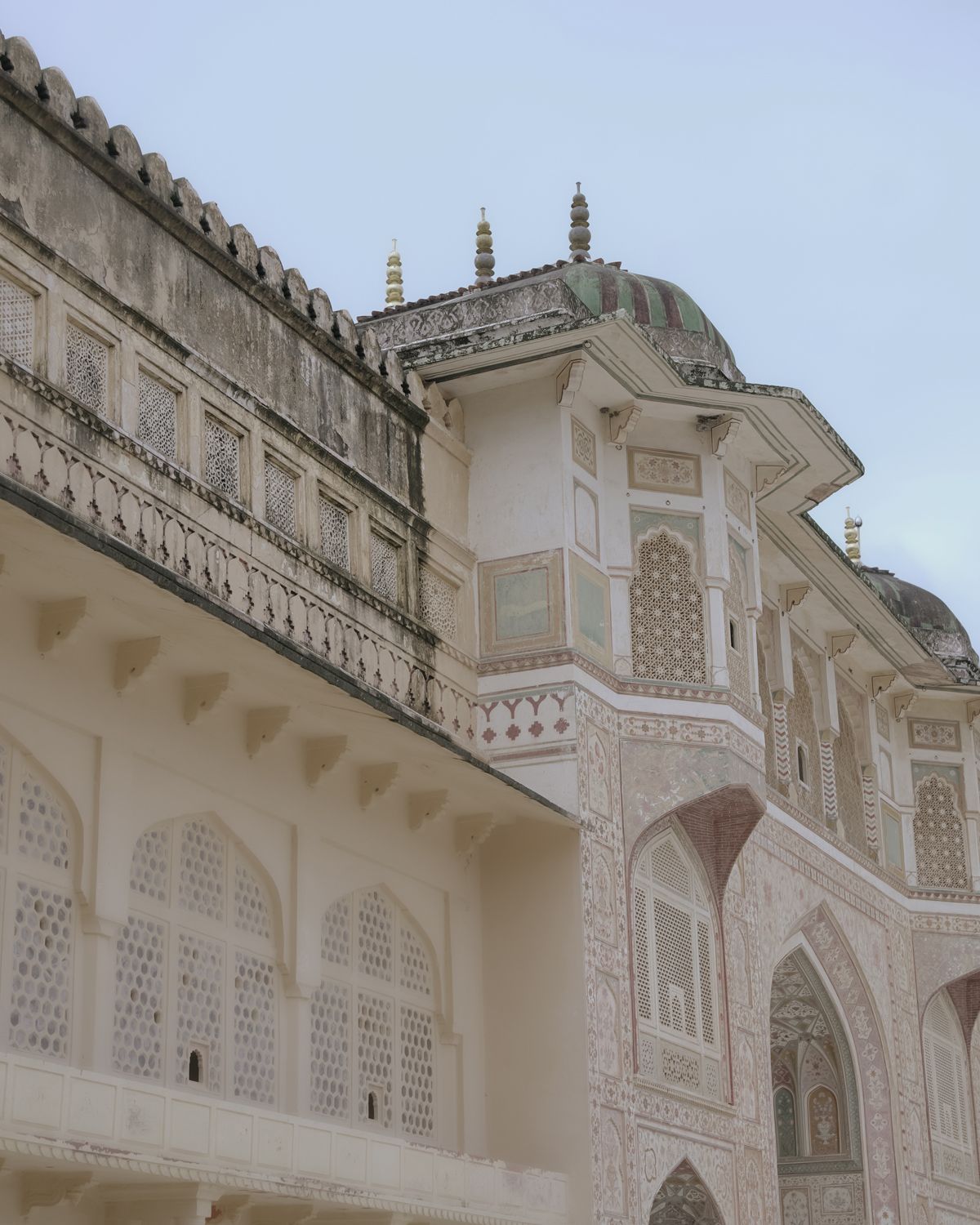 Ornate white marble facade of a historic Indian palace with intricate lattice work and decorative arches.