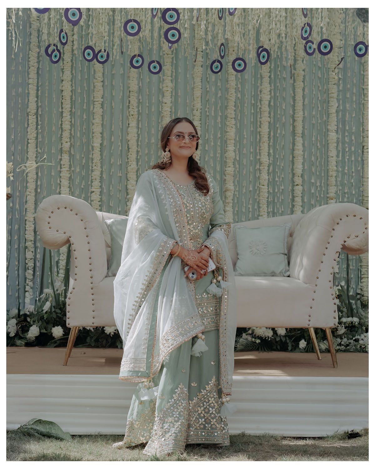Elegant scene with white chaise lounge against blue-decorated backdrop and person in traditional attire.