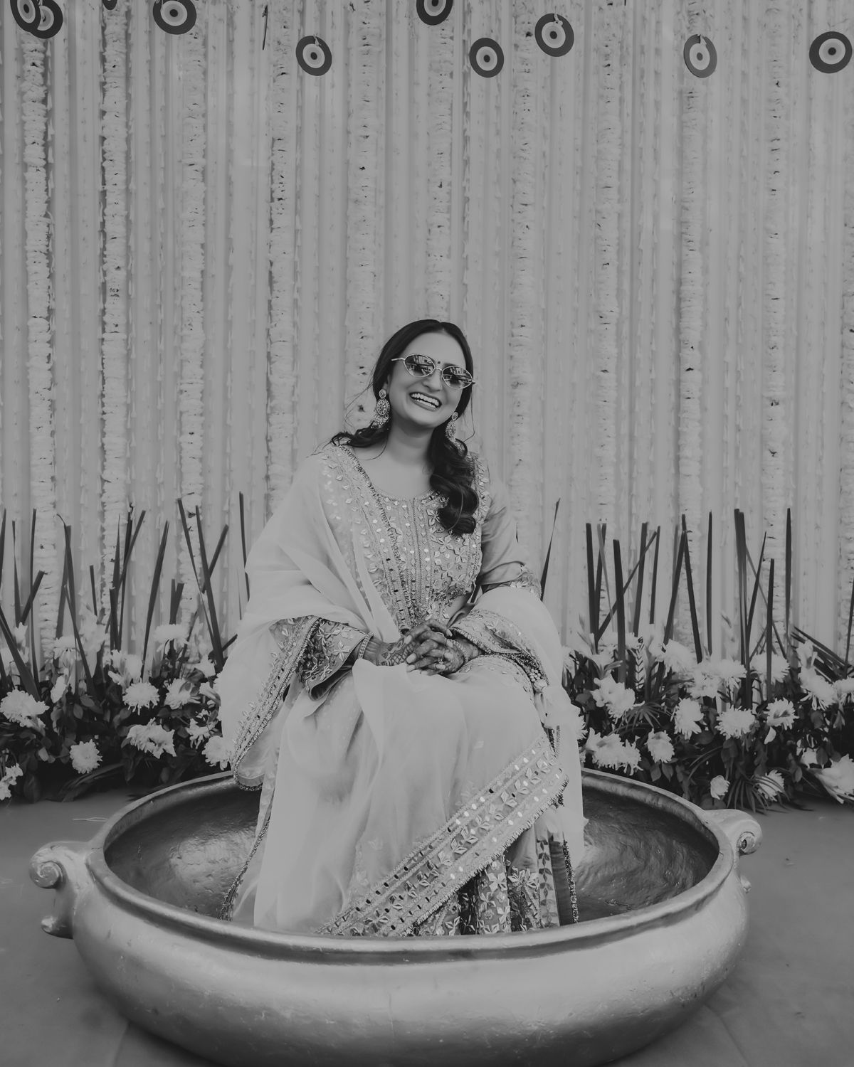 Black and white portrait of someone in elegant attire seated in a decorative bowl setting.