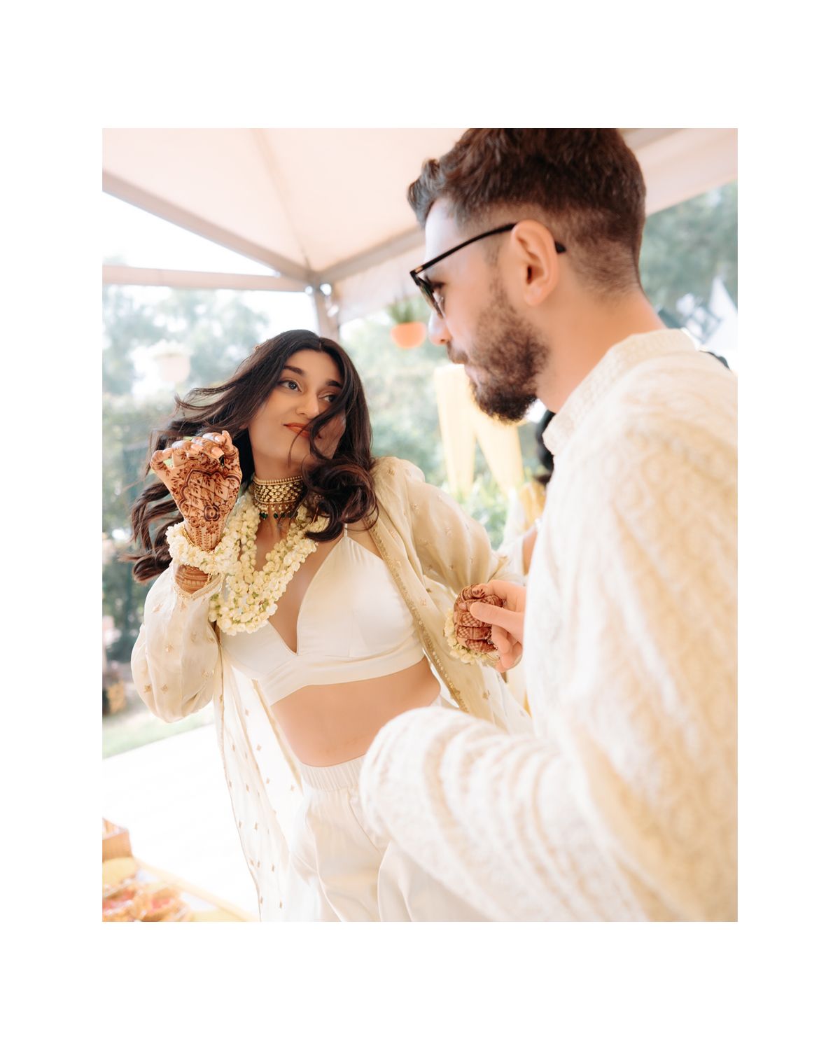 Couple enjoying a joyful moment together at an outdoor celebration wearing white and gold outfits.
