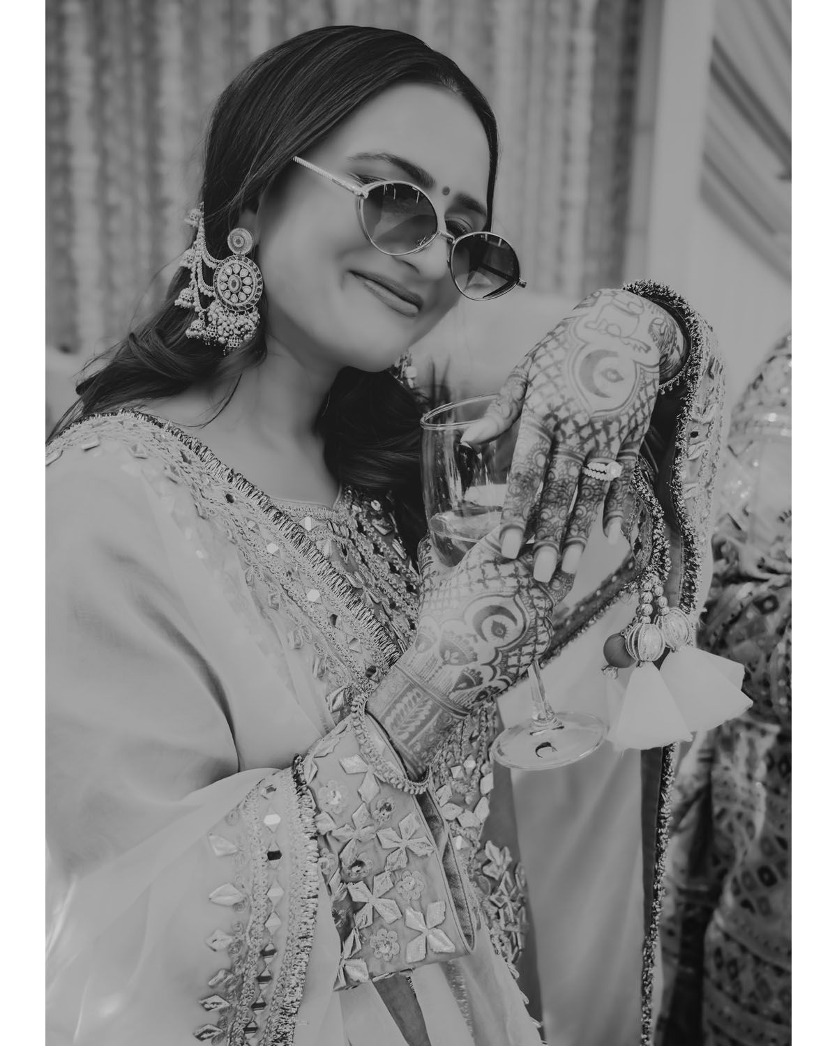 Black and white portrait showing intricate henna designs and traditional jewelry details.